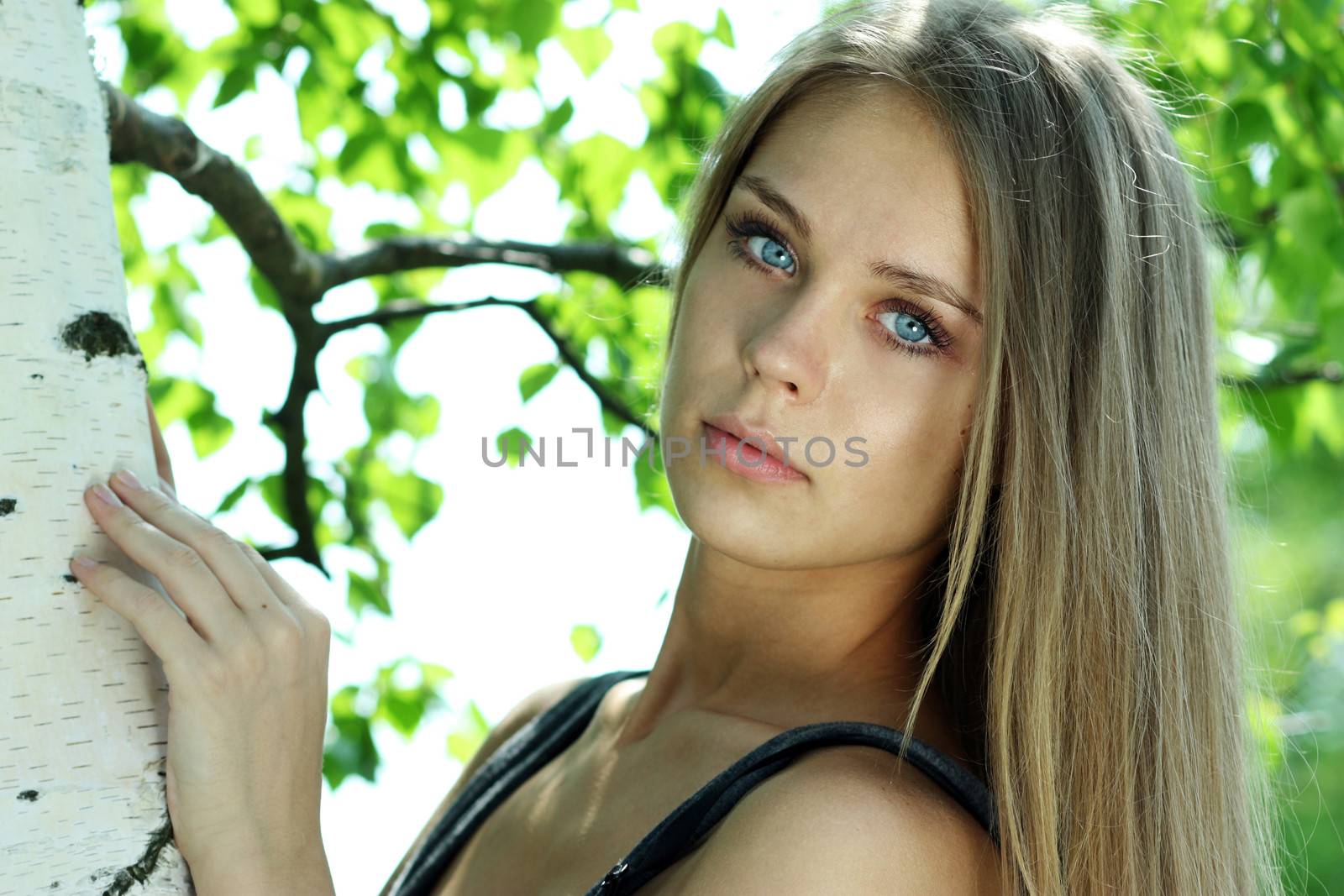 Portrait of the young beautiful woman on a background of leaves of a birch