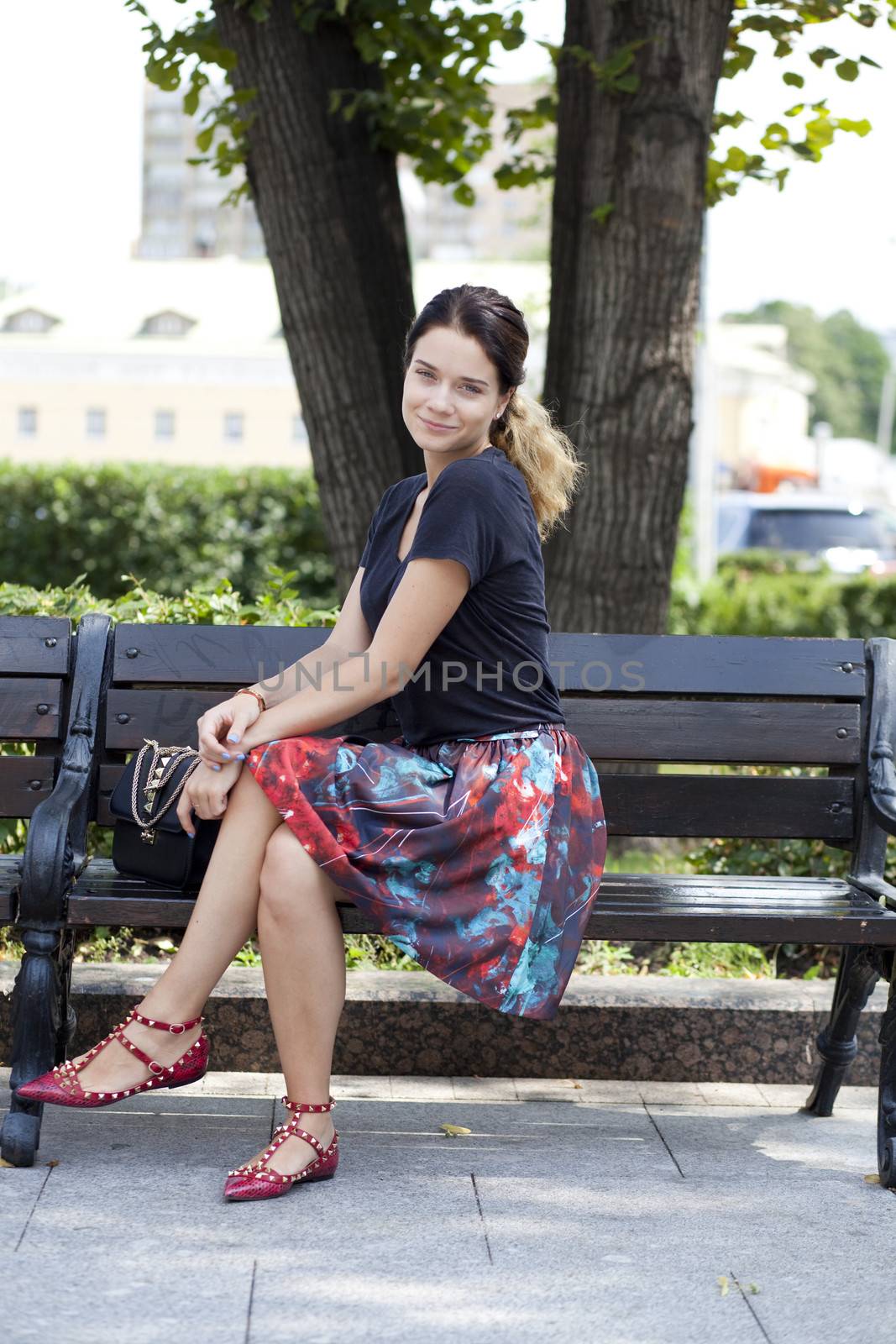 Beautiful young woman sits on a bench