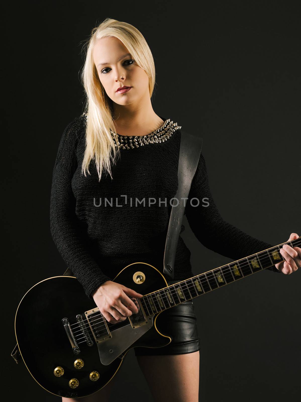 Photo of a sexy blond female playing a black electric guitar.