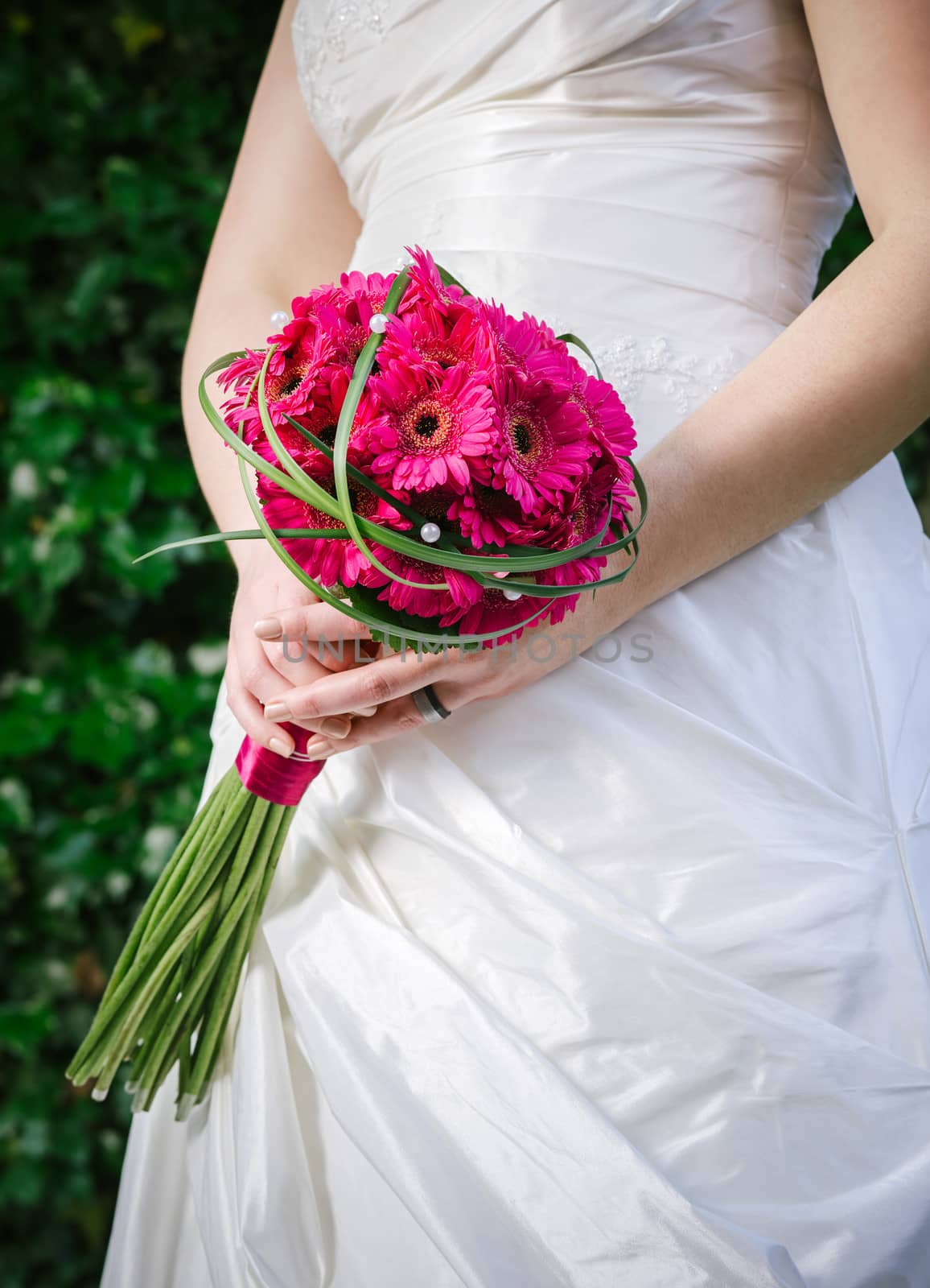 Photo of a bride in a white dress holding flowers.
