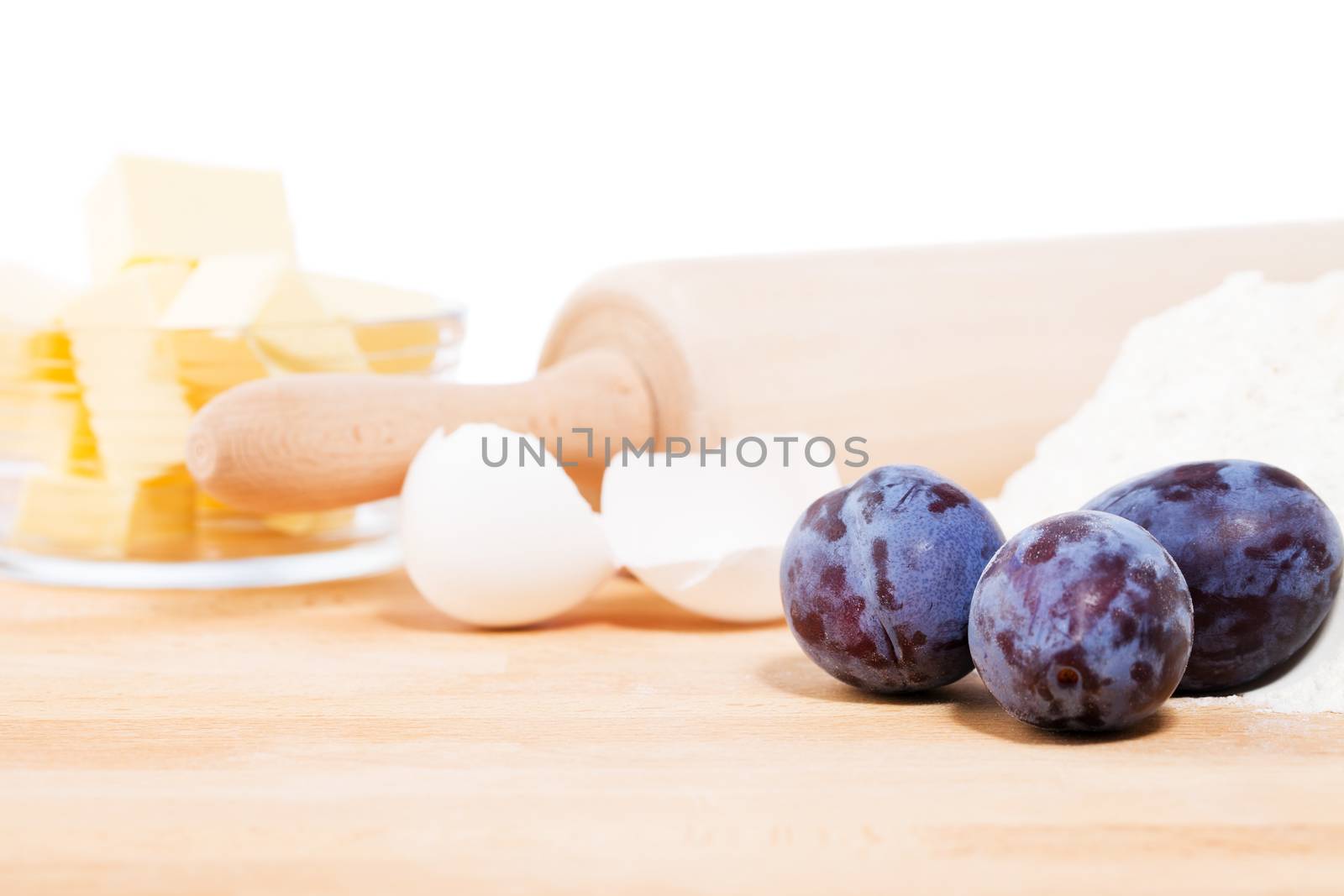 closeup of plums for baking in front of baking ingredients and tools