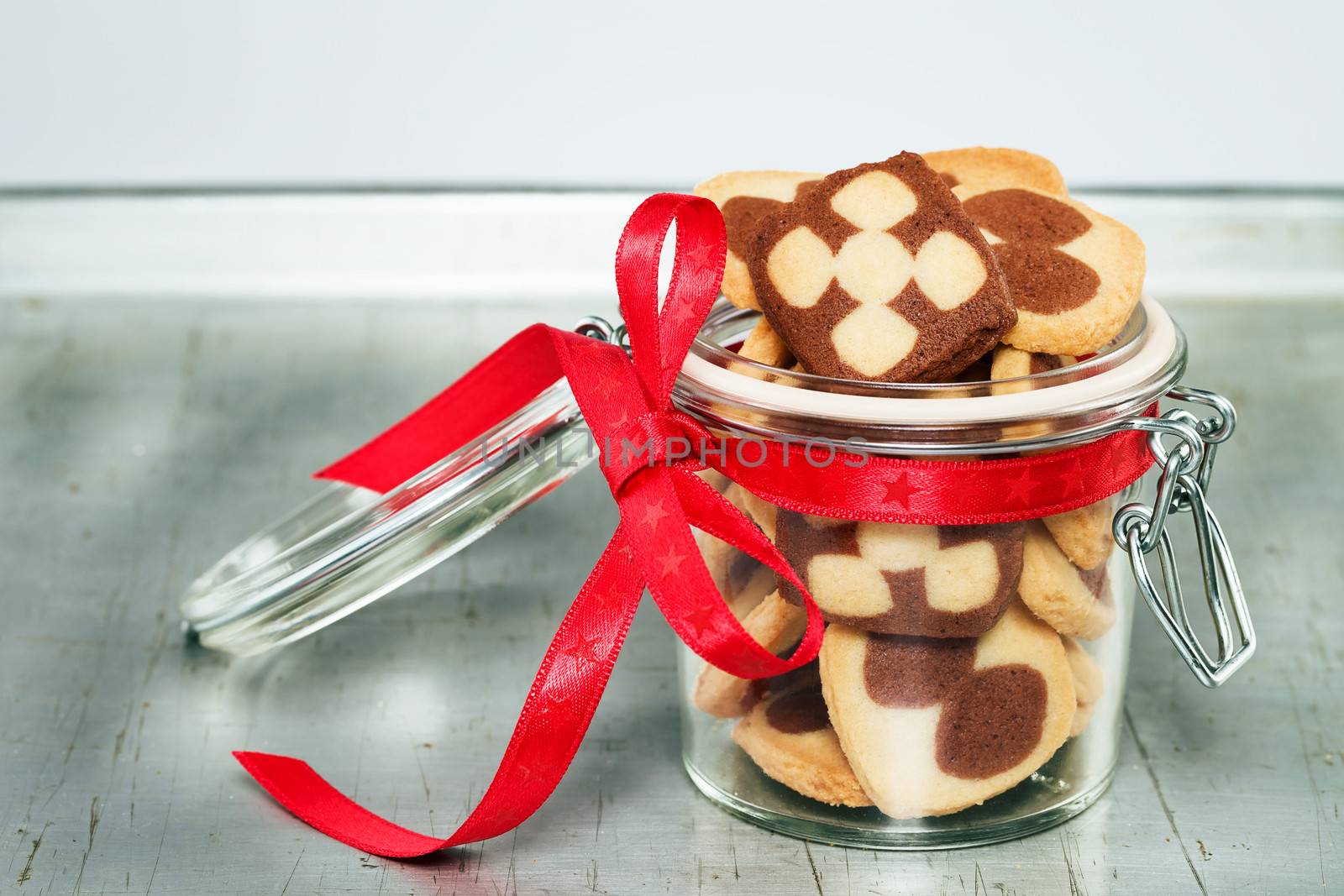 a jar filled with christmas cookies on a silver metal tray