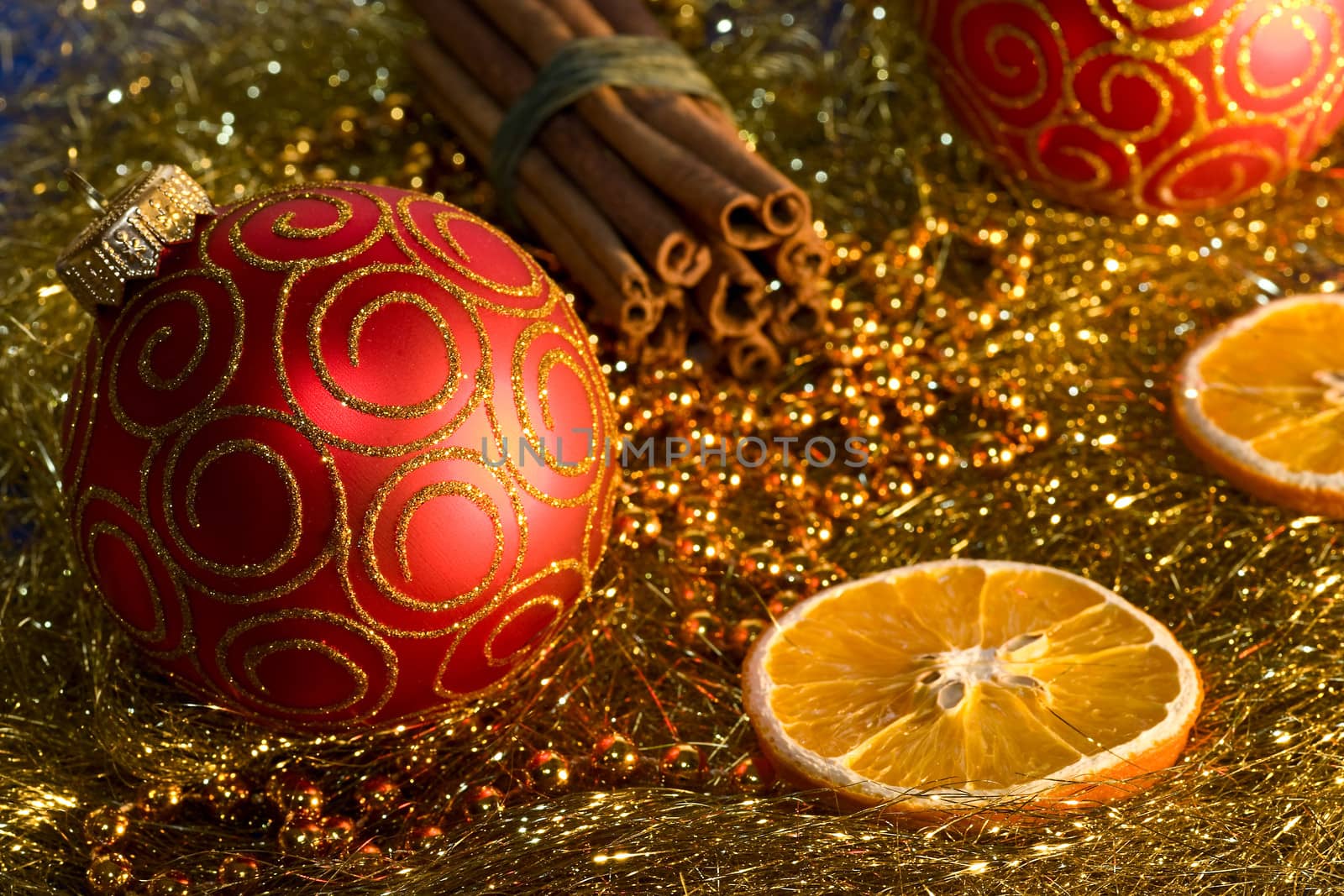 red christmas ball, cinnamon,   orange and beads on gold background 