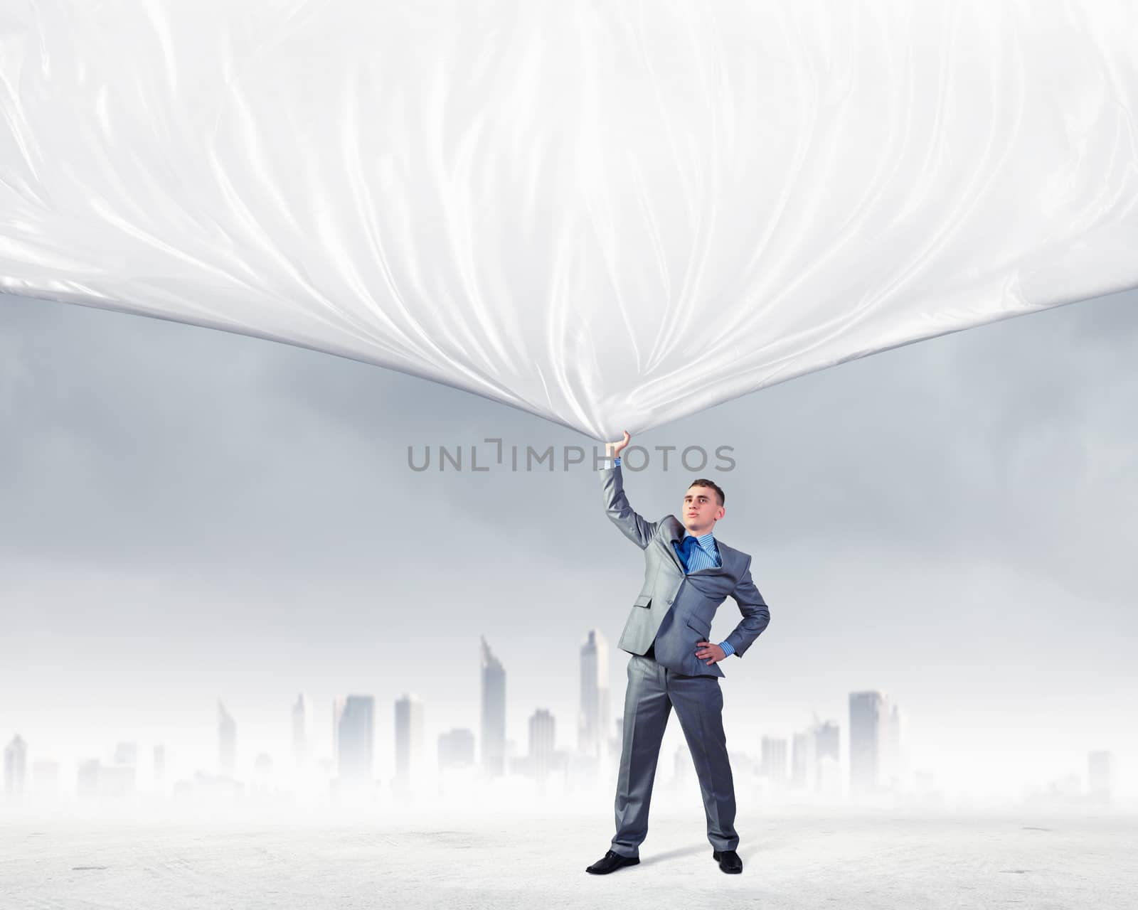 Image of young businessman pulling blank banner from above