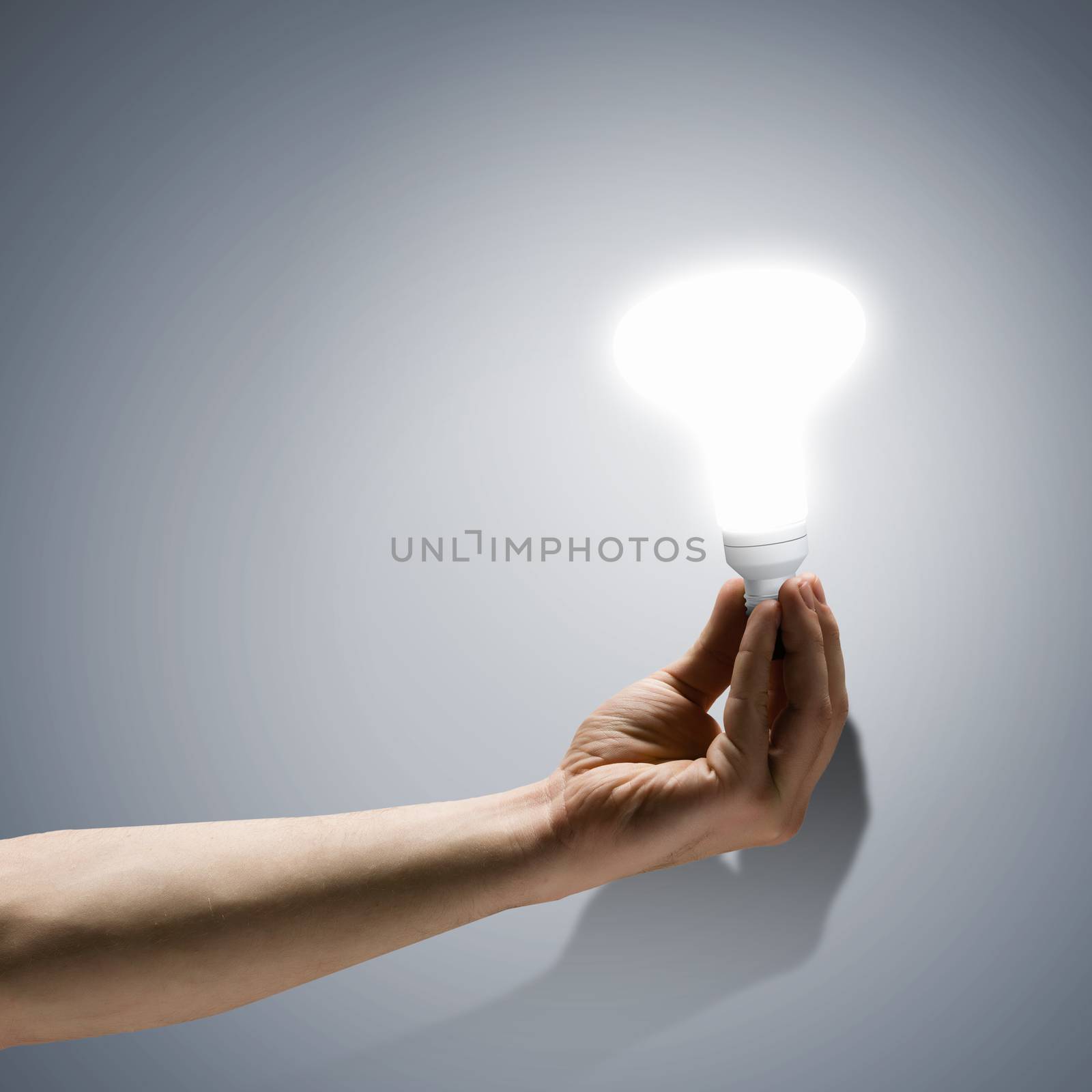 Close up image of human hand holding electrical bulb