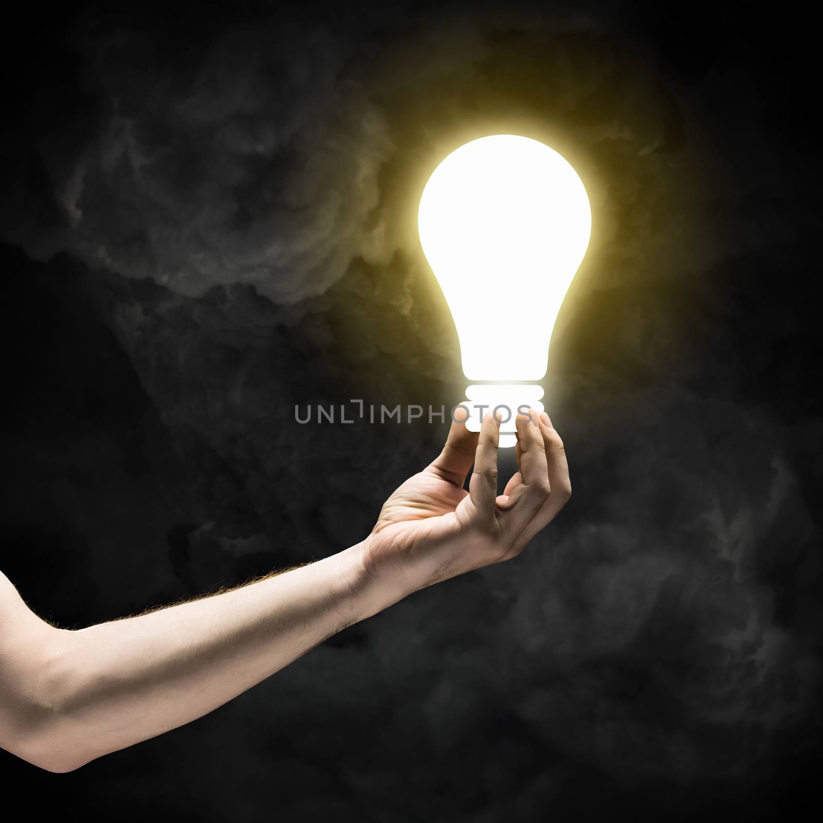 Close up image of human hand holding electrical bulb in darkness
