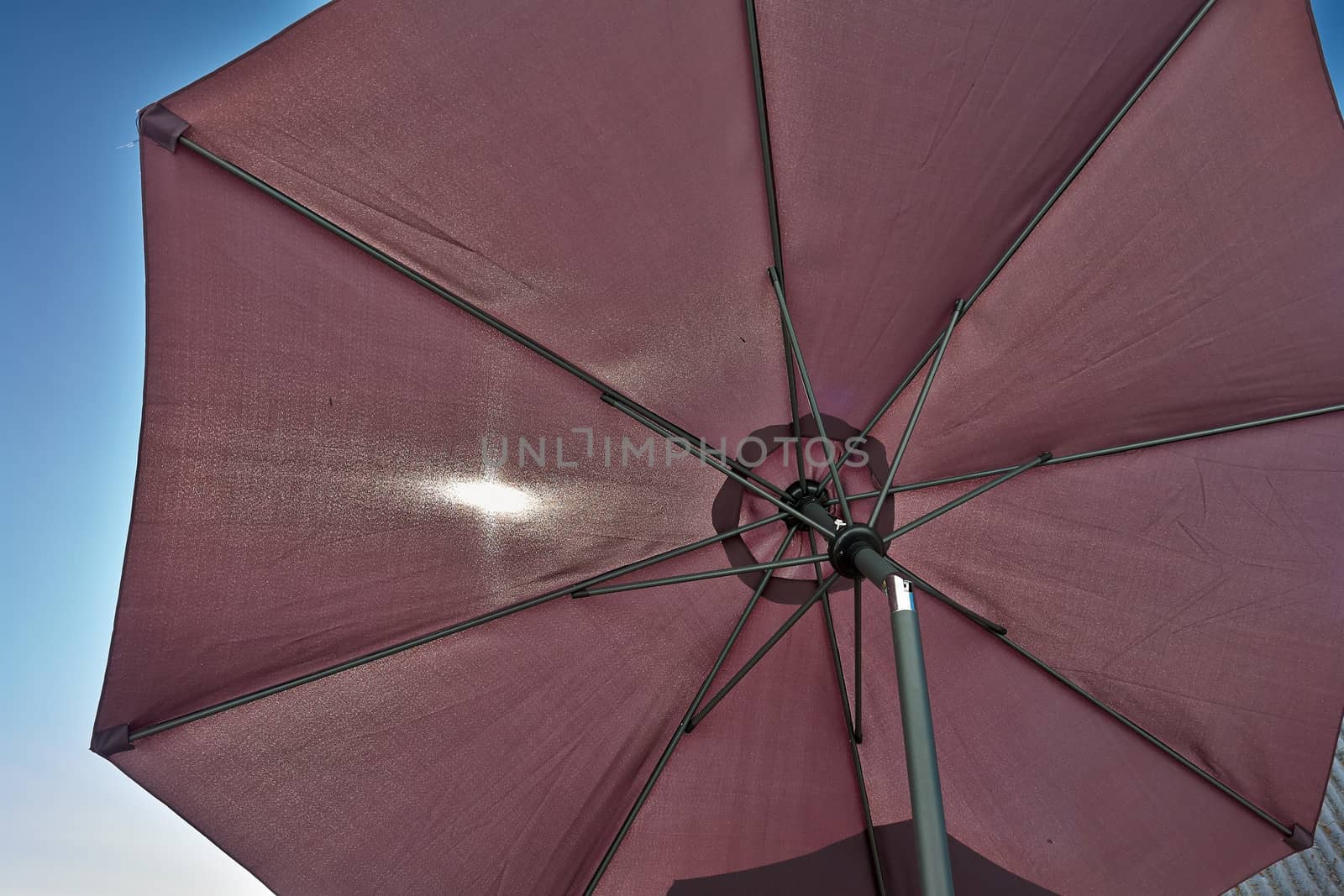 Details of an open brown beach umbrella parasol