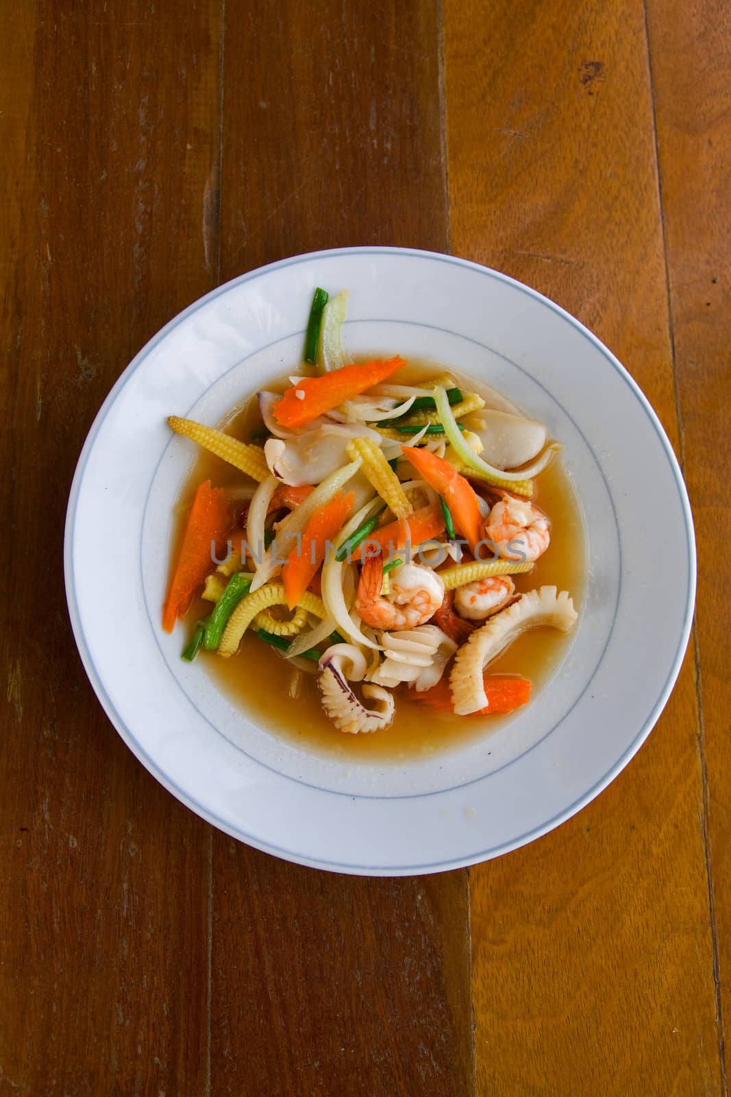 fried vegetables with seafood on white plate on the table