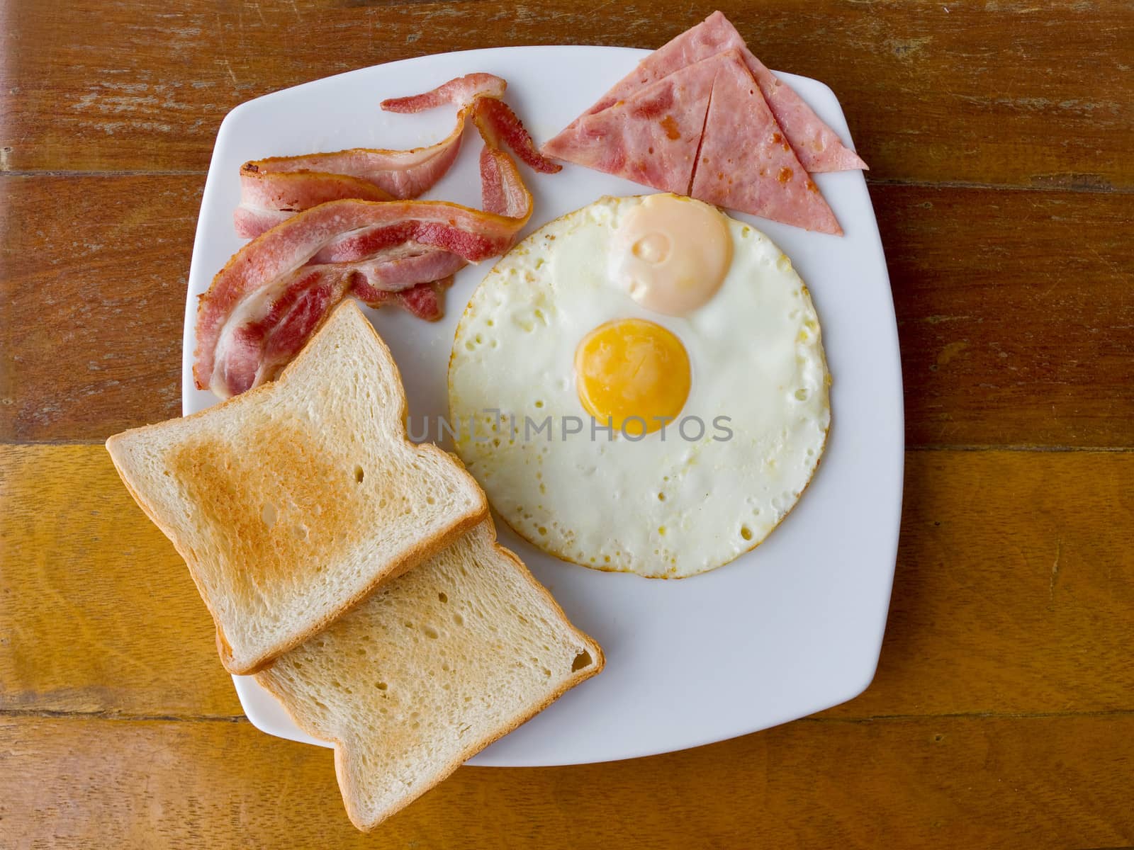scrambled eggs with bacon and  toast  on white plate on the table