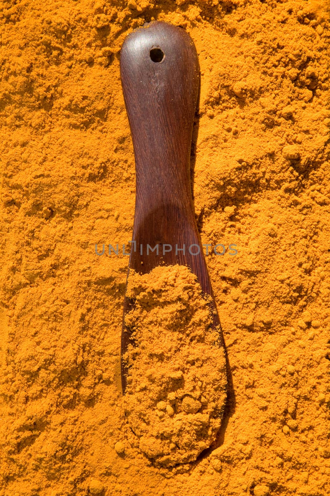 Turmeric powder spice pile with spoon