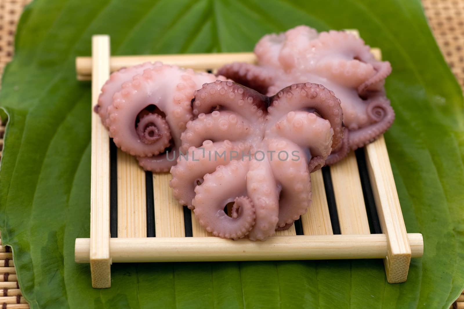 Delicious cooked octopus on wood tray and green leaf