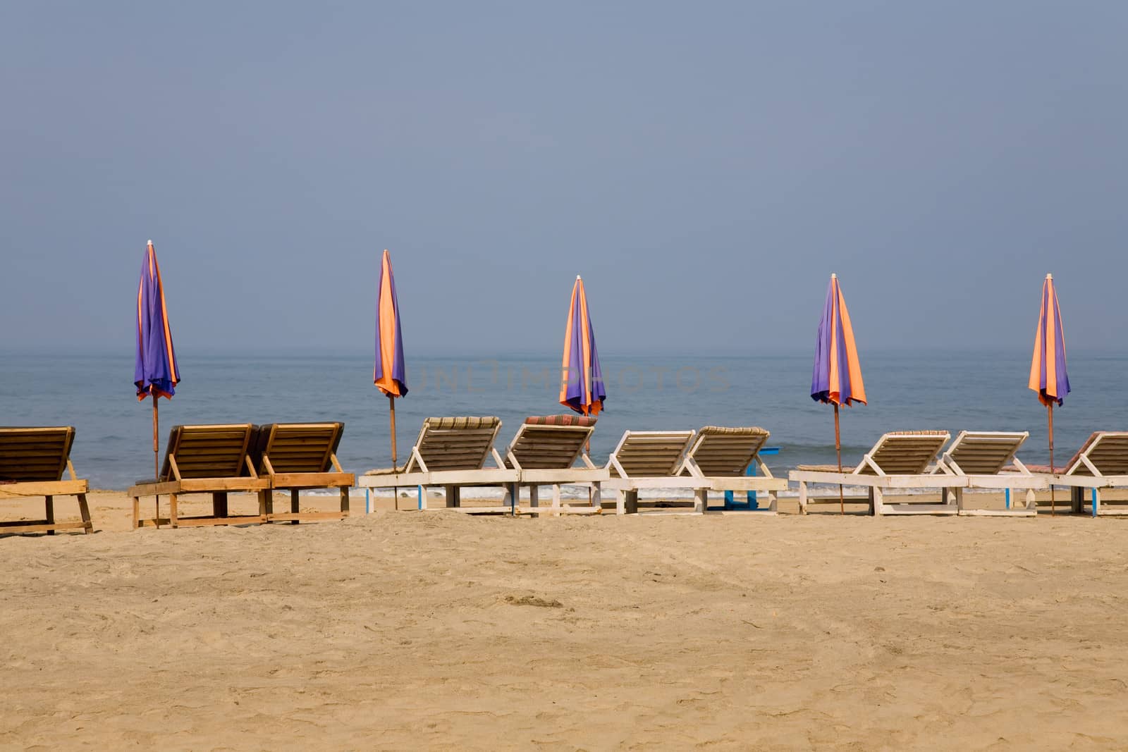 sun loungeres and  Umbrellas against  blue sea at sun day in Goa, India