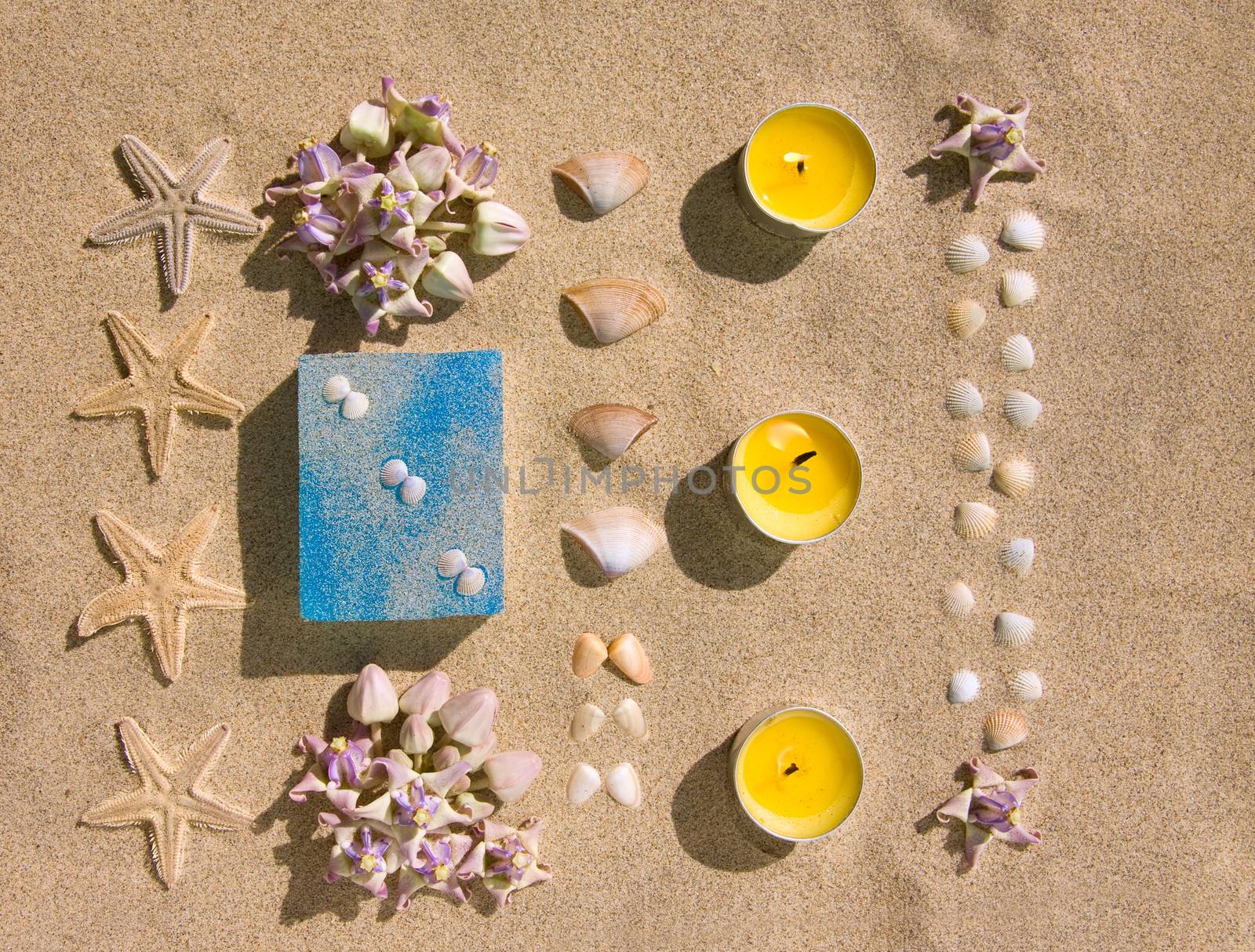 bar of natural handmade soap on sand with flower,  star and shell