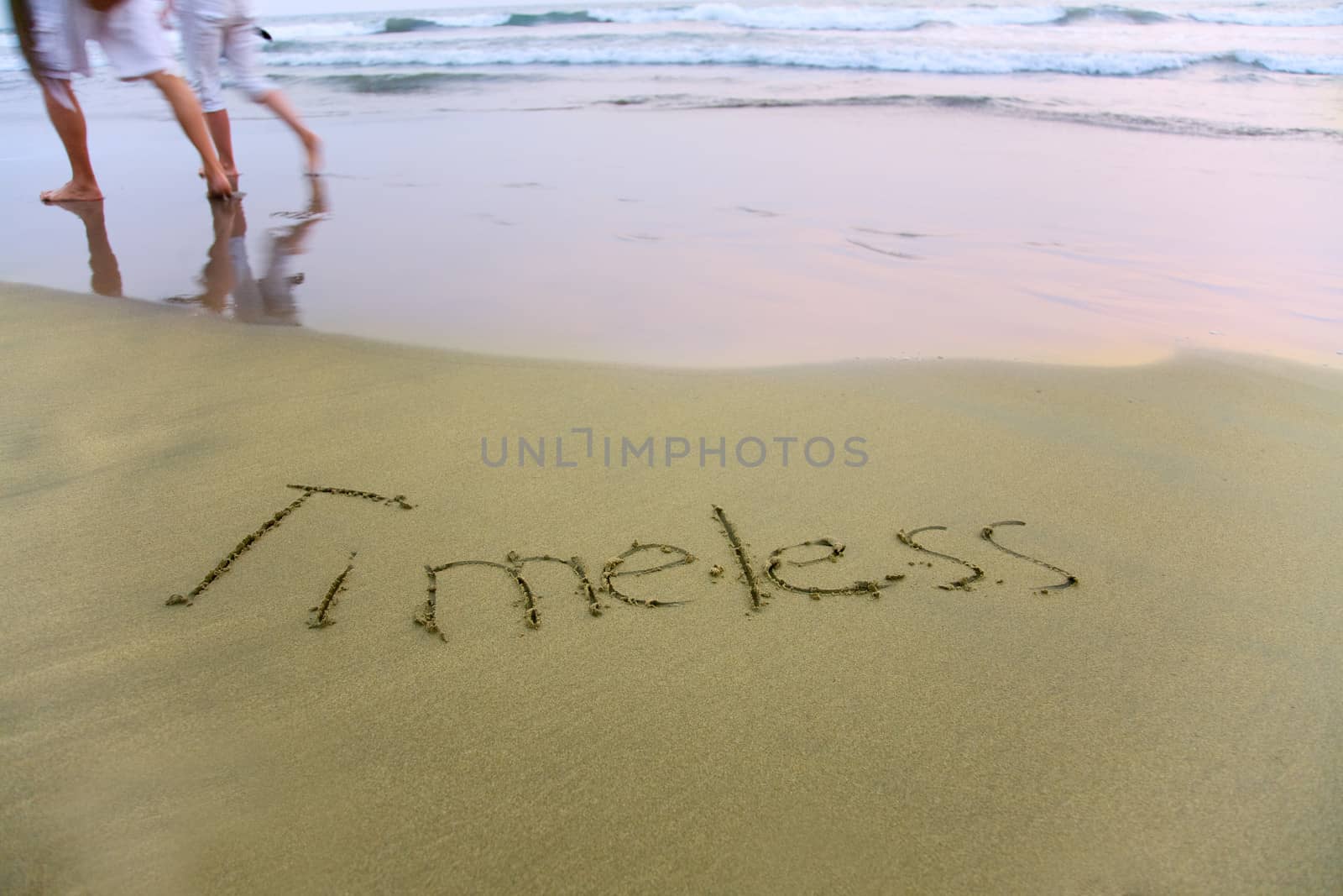 Handwriting word Timeless written  on the sand 
