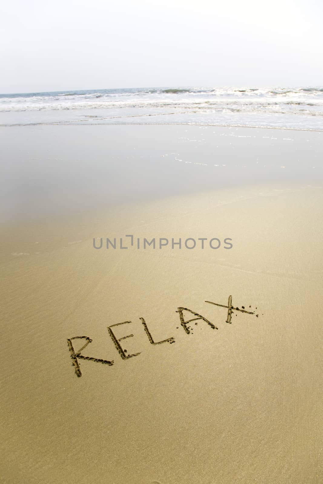 Handwriting word Relax written  on the sand 