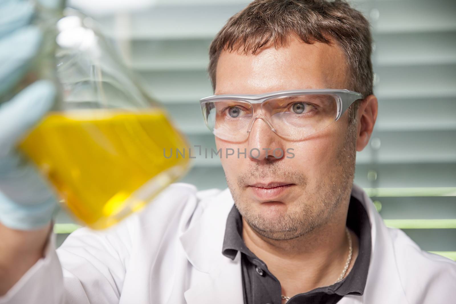 A man with a yellow liquid in the laboratory