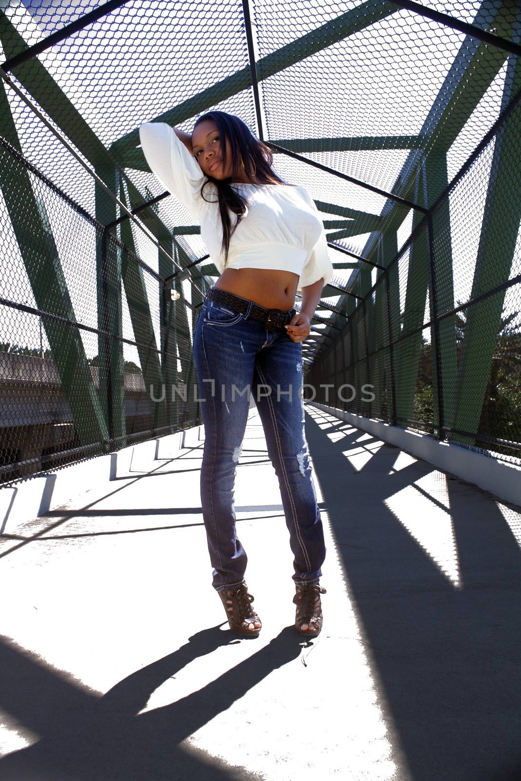 A lovely young Haitian girl on a pedestrian overpass covered with chain-link fence.