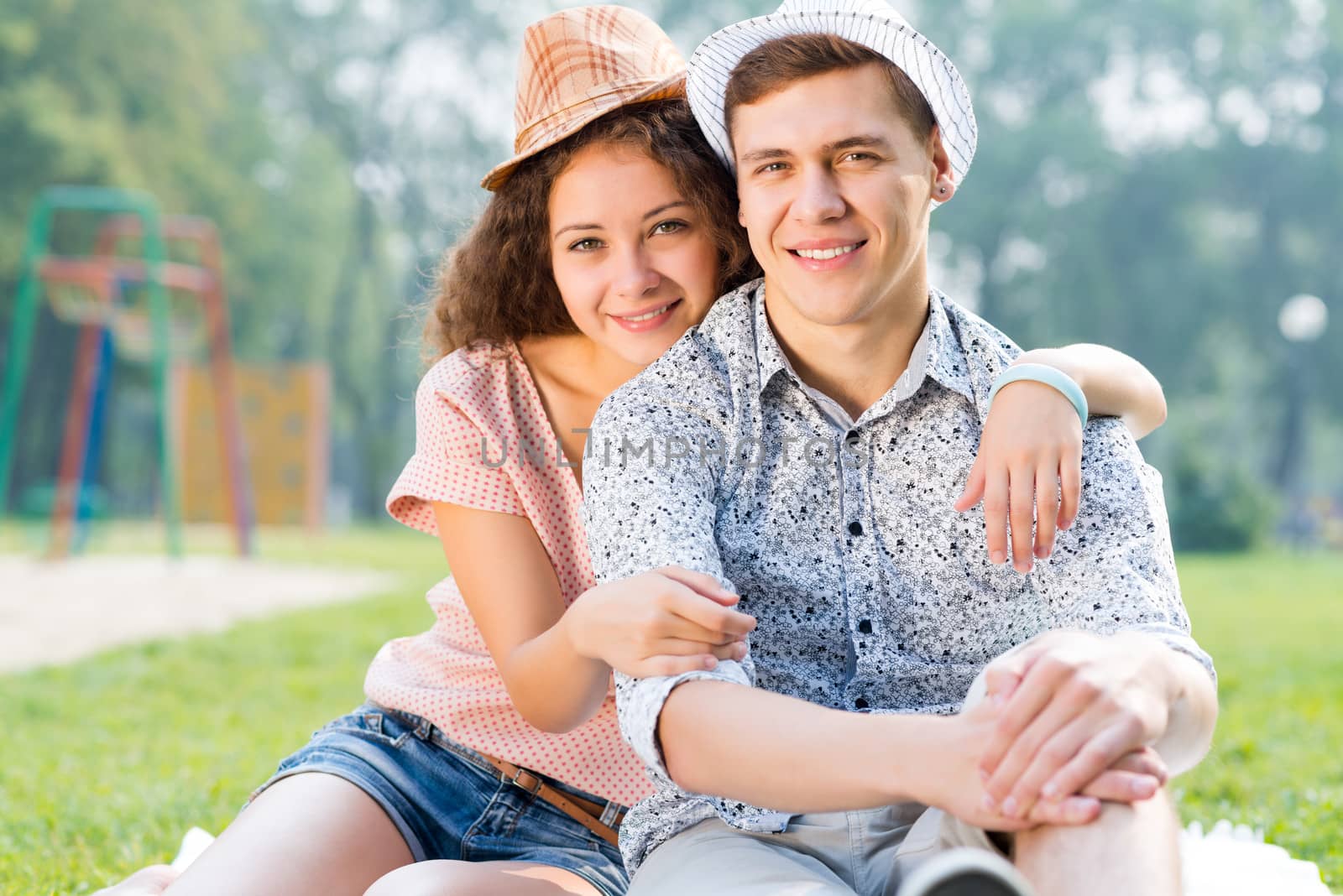 romantic couple lying on the grass in the summer park, spending time with loved ones