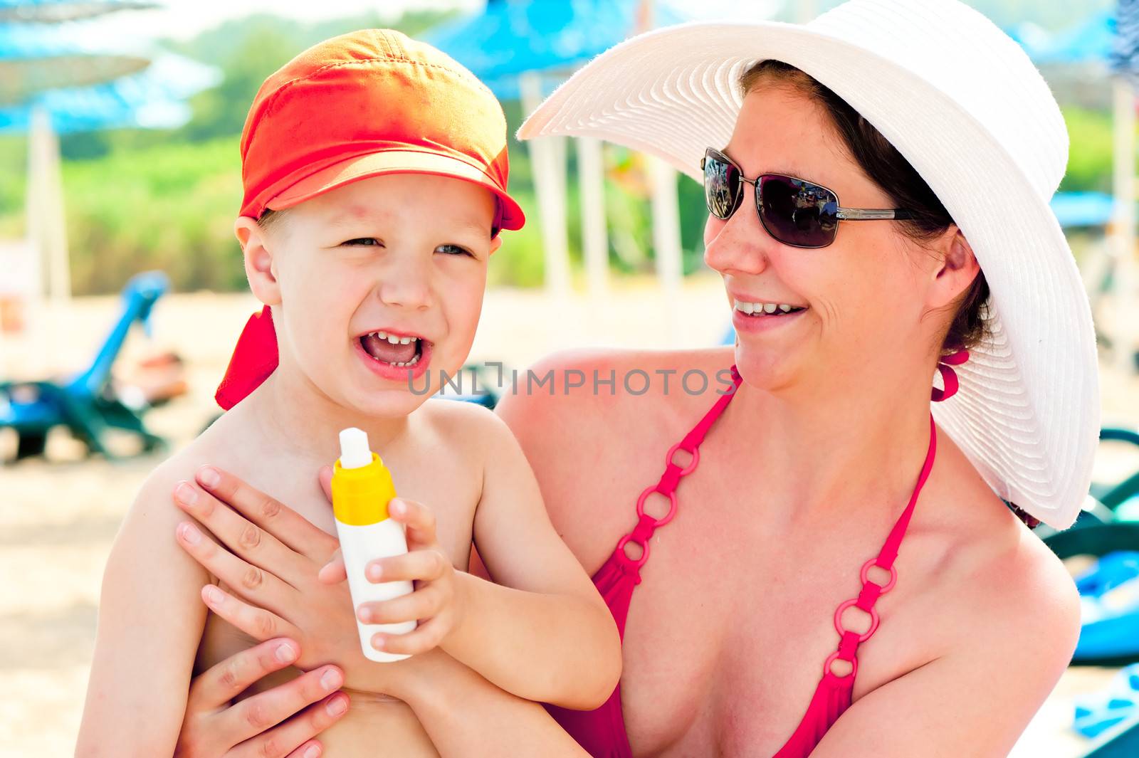 Mom and son on the beach to protect the skin from sun lotion by kosmsos111