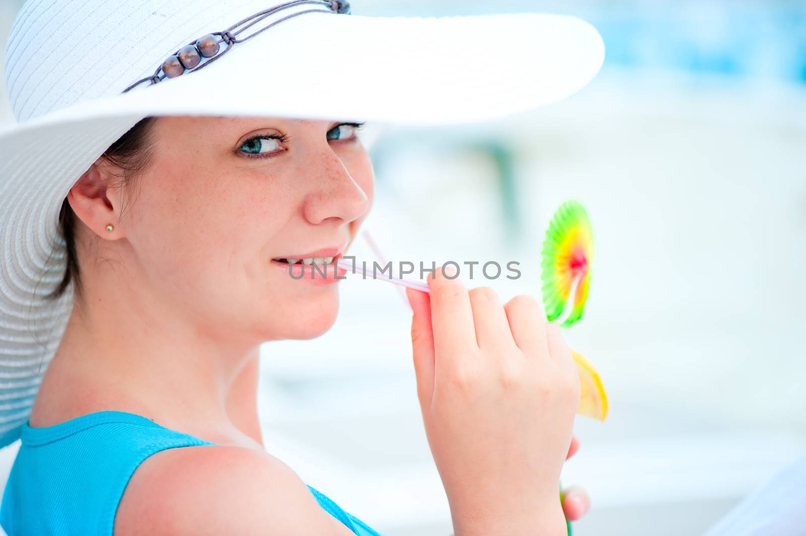 smiling woman in white hat drinking a cocktail