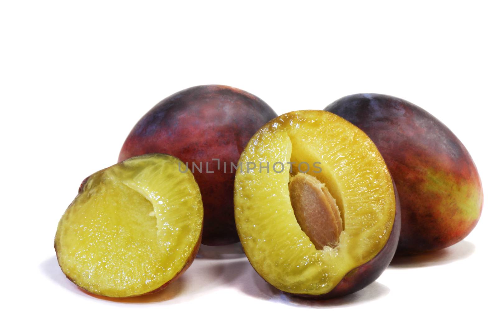 Large ripe plum and one exploded drain on white background