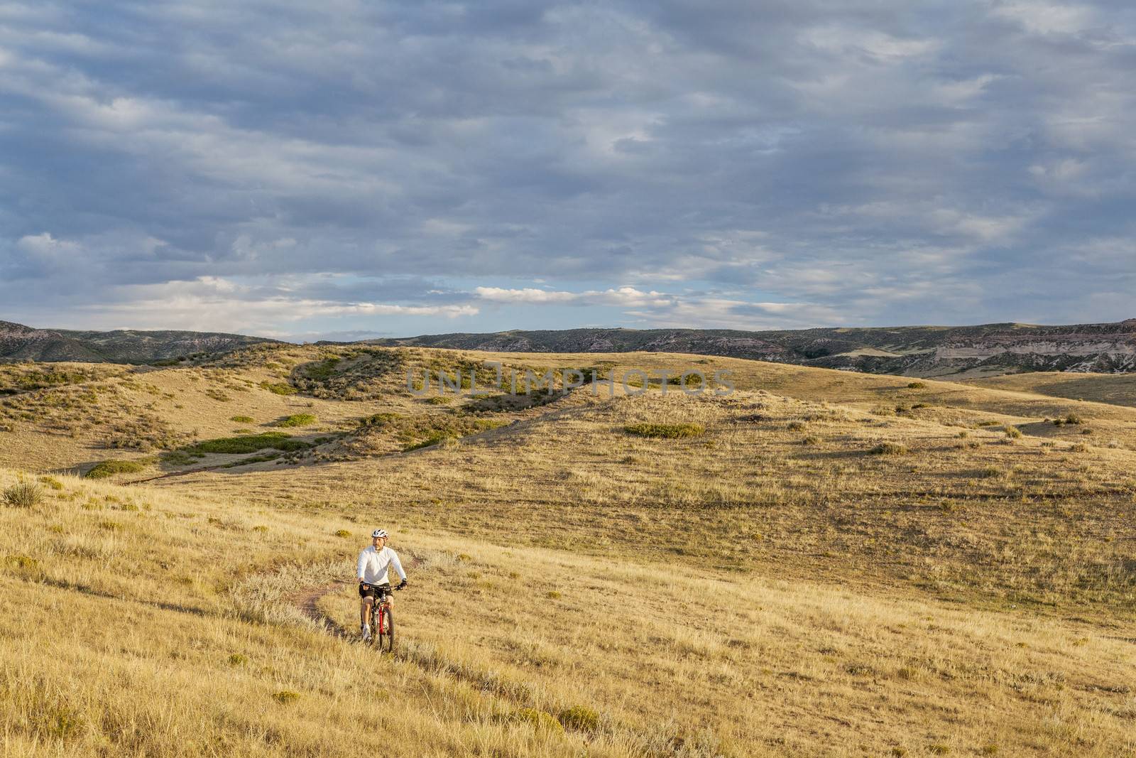 a lonely male biking over rolling prairie illuminated by sunrise at Soapston Prairie Natural Area in northern Colorado near Fort Collins, late summer