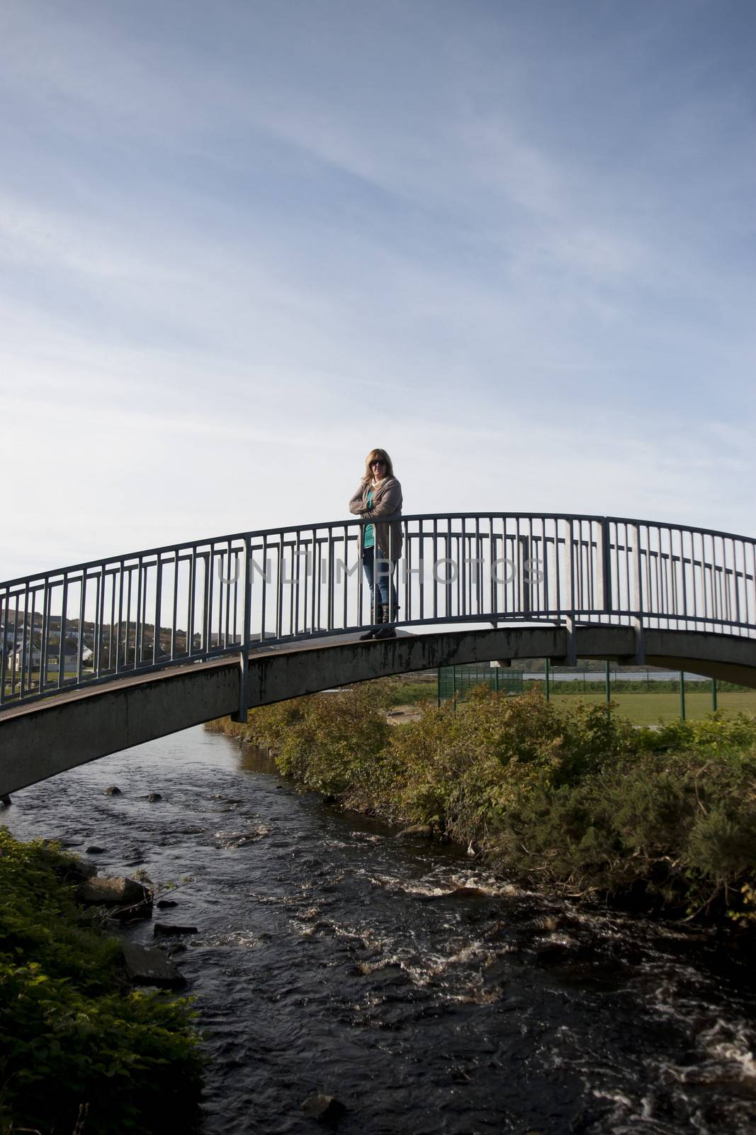 woman silhouetted walking on a modern bridge by morrbyte