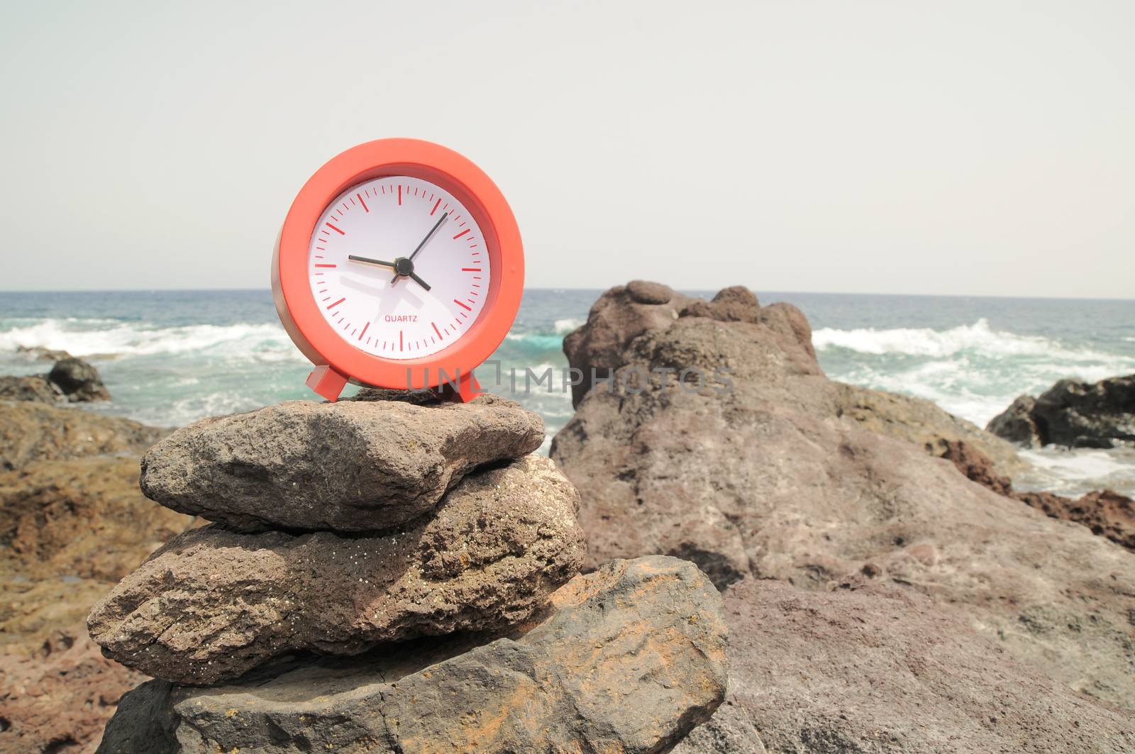 One Red Clock on the Rocks Near the Ocean 