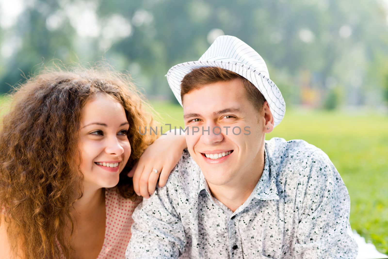 romantic couple lying on the grass in the summer park, spending time with loved ones