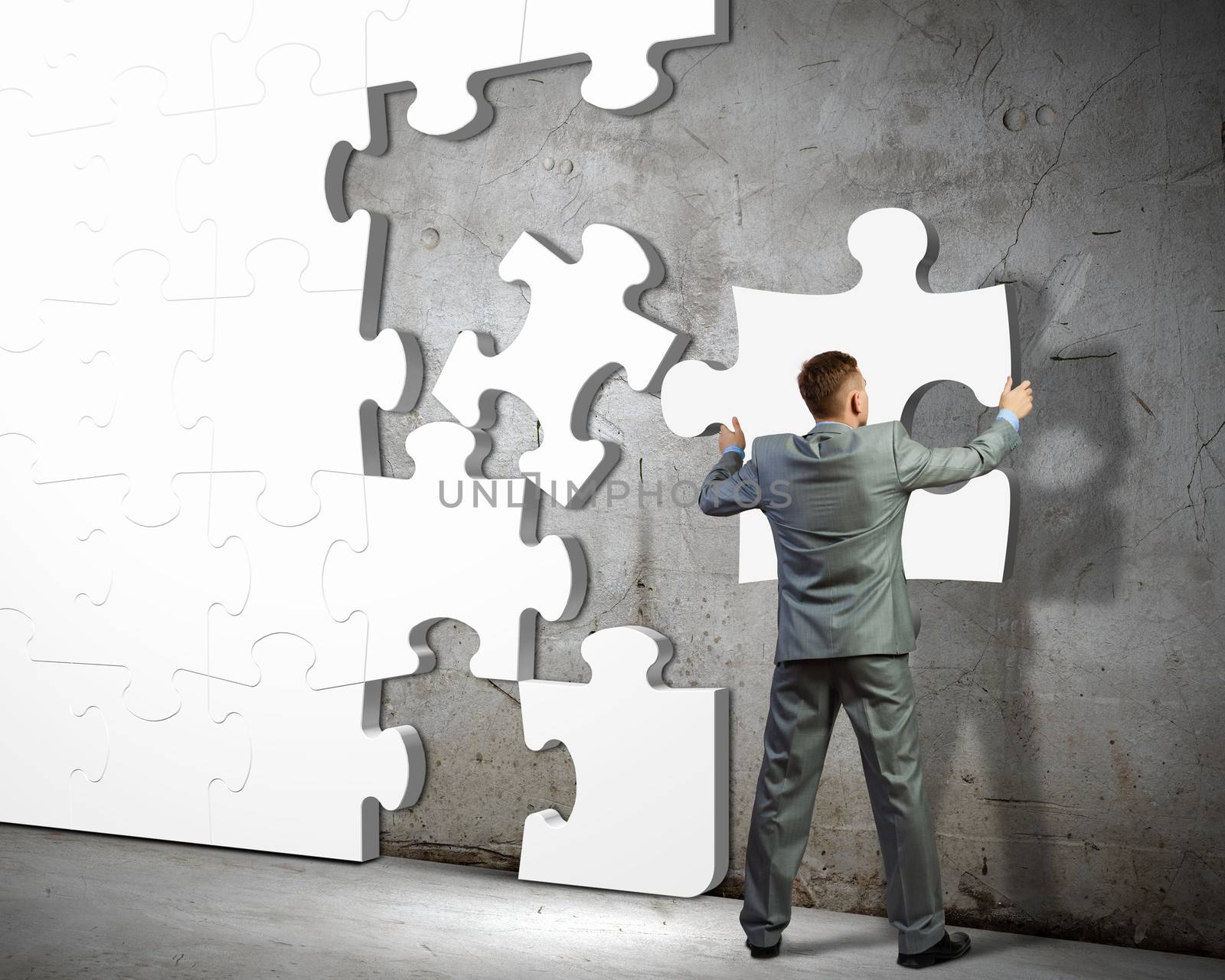 Image of businessman compiling macro white puzzle. Building business