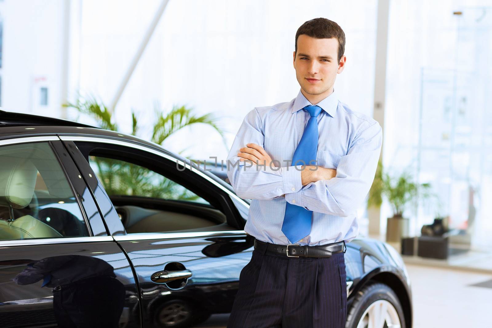 Image of handsome young businessman in suit standing near car