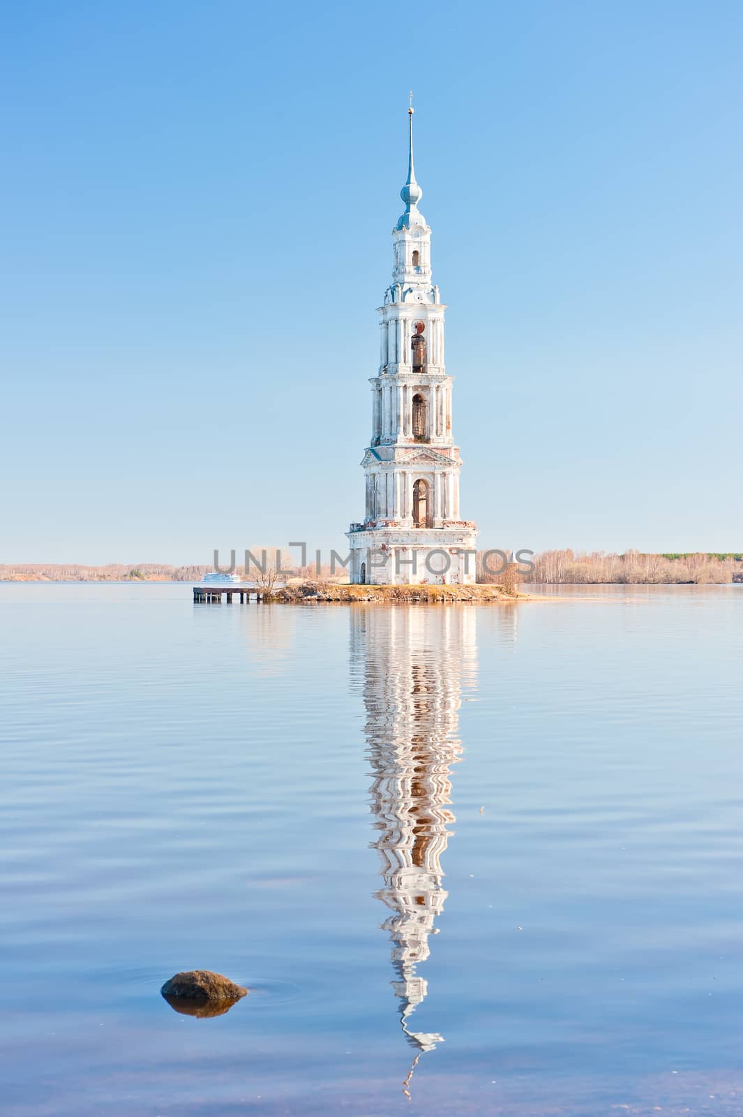 High belltower in the middle of the wide river