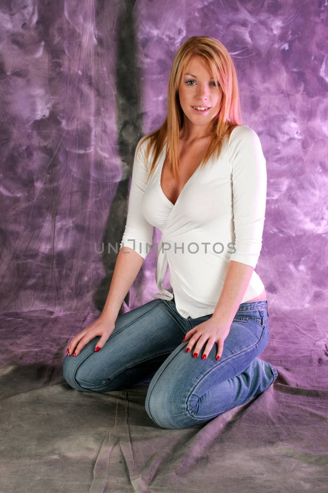 Beautiful blonde model sitting on her knees on the floor, facing the camera. The model is set against a purple background, which can be eliminated thanks to the clipping-path included in the JPG file.