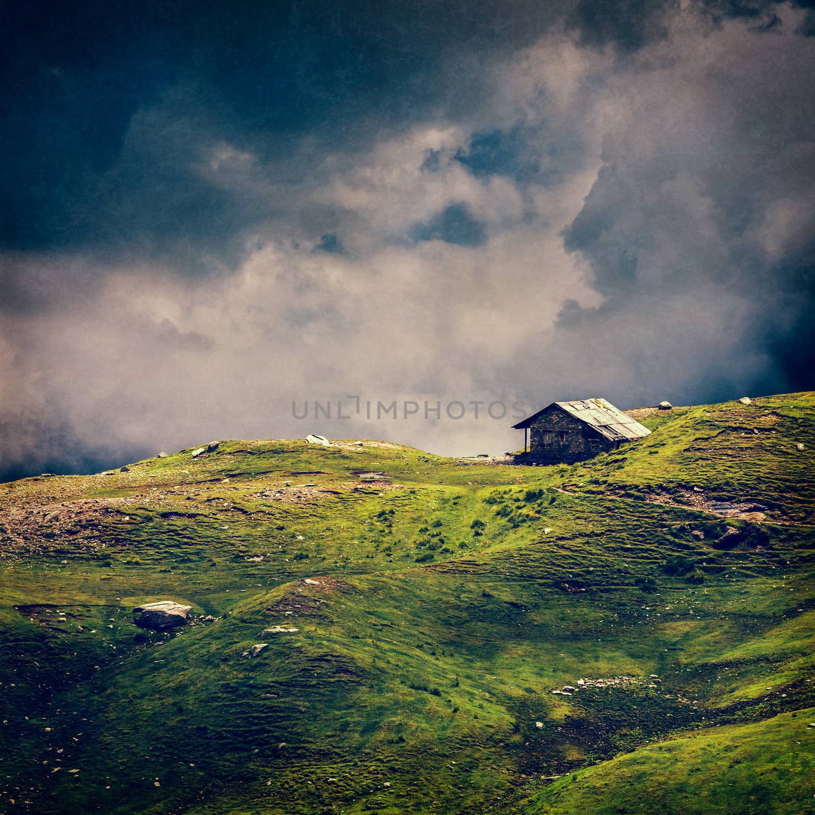 Serenity serene lonely scenery background concept - old house in hills in mountins on alpine meadow in clouds. VIntage style cross process, grain and texture added