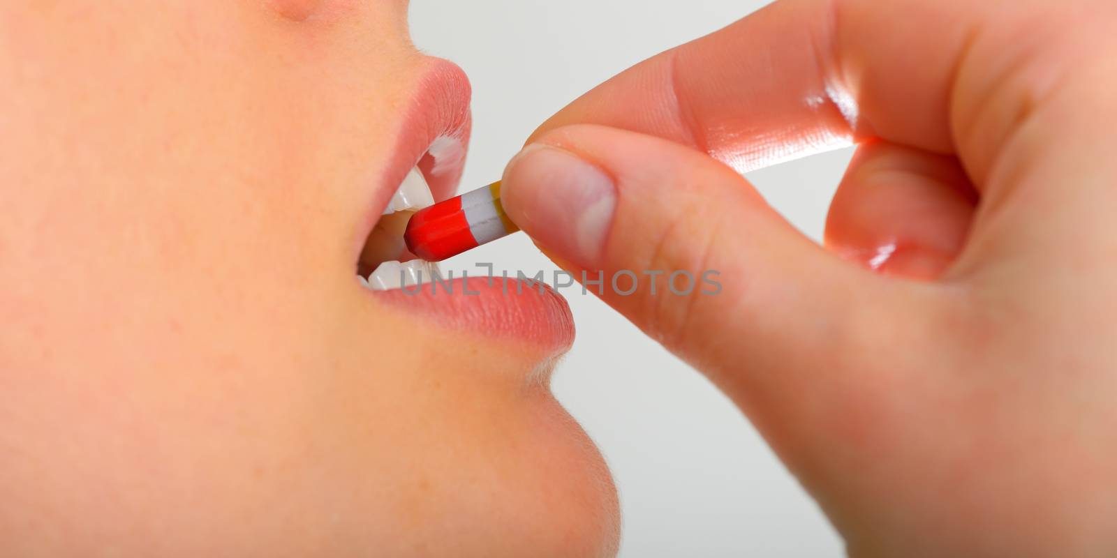 young woman taking pill close up