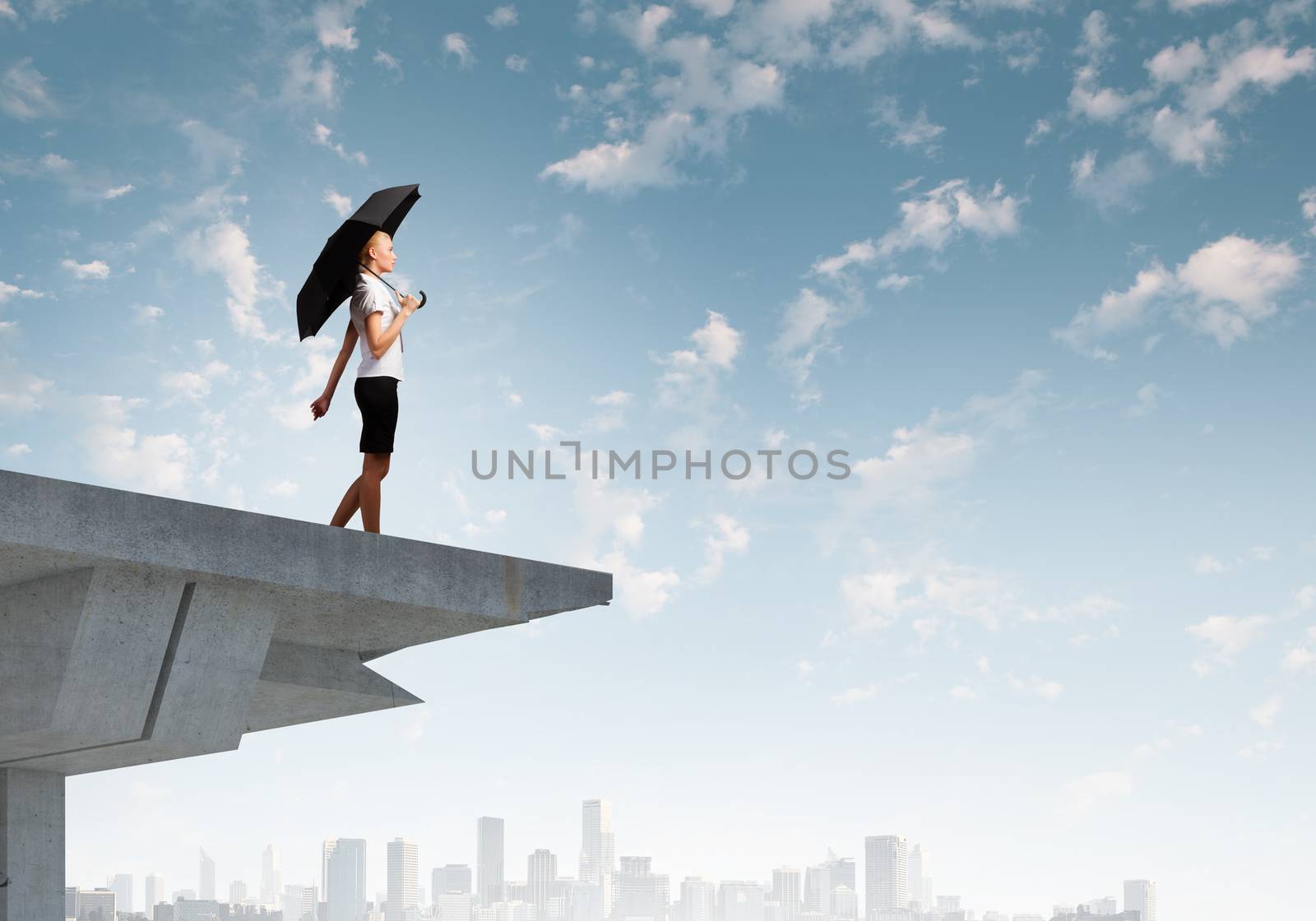 Young businesswoman with umbrella standing on bridge
