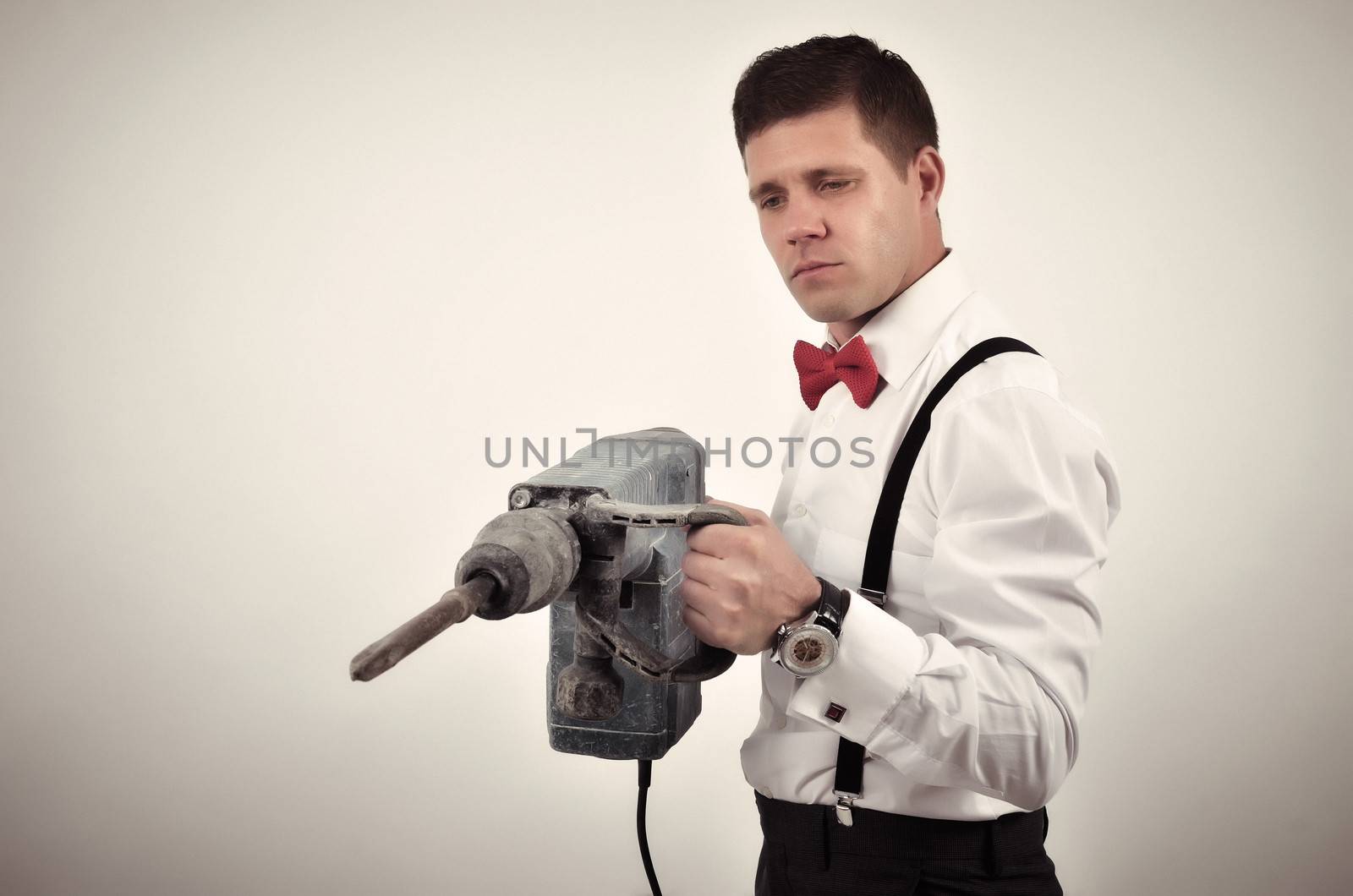 Elegant businessman with heavy perforator in his hands
