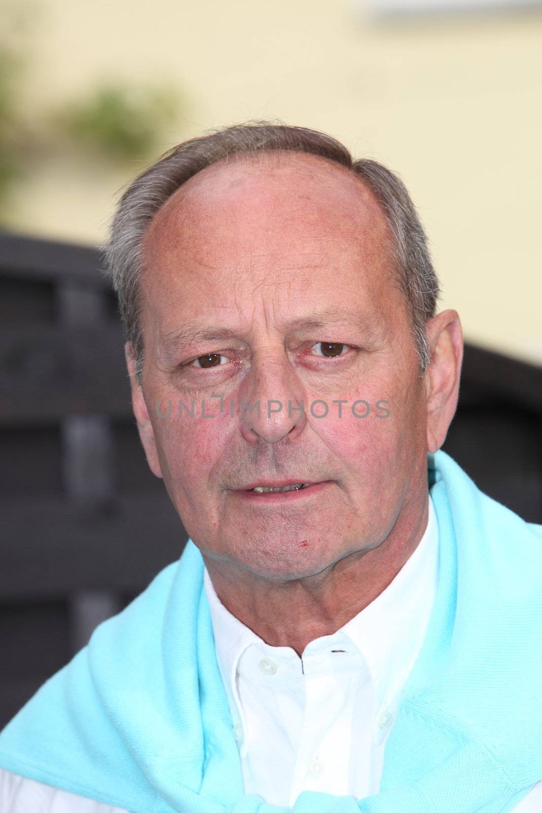 Head and shoulders portrait of an attractive serious senior man looking pensively at the camera