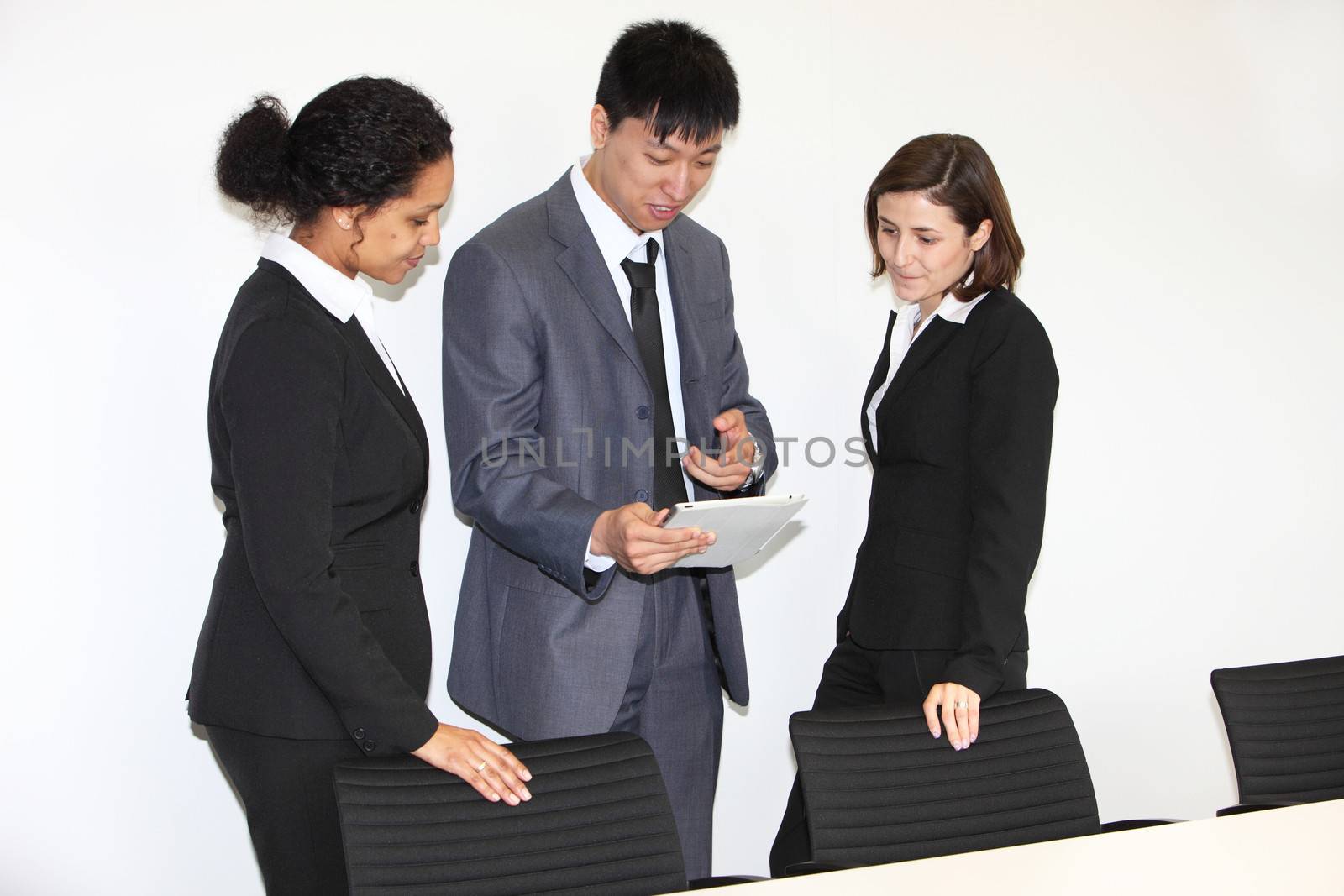 Three diverse multiethnic businesspeople having a discussion standing looking at a tablet-pc in the office