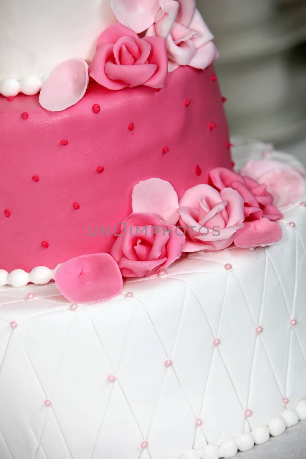 Tiered wedding cake decorated with pink roses made of icing sugar to match the pink and white alternating tiers