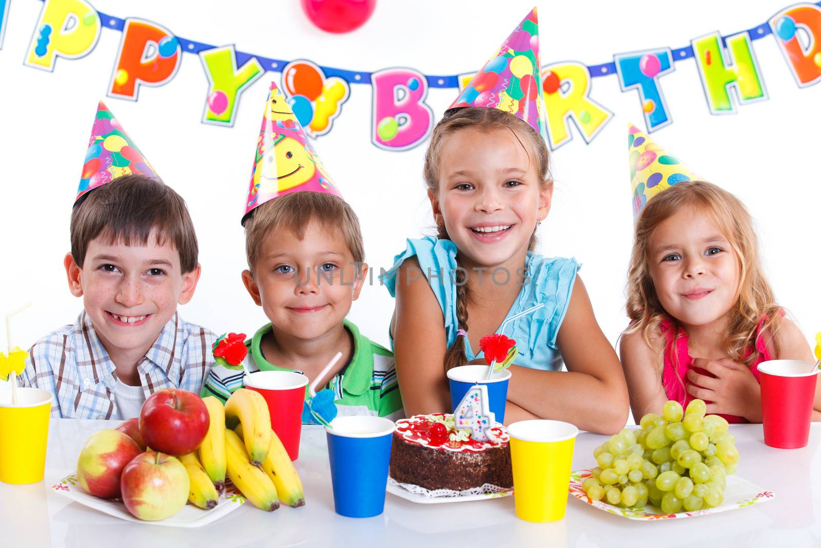 Group of adorable kids having fun at birthday party with birthday cake