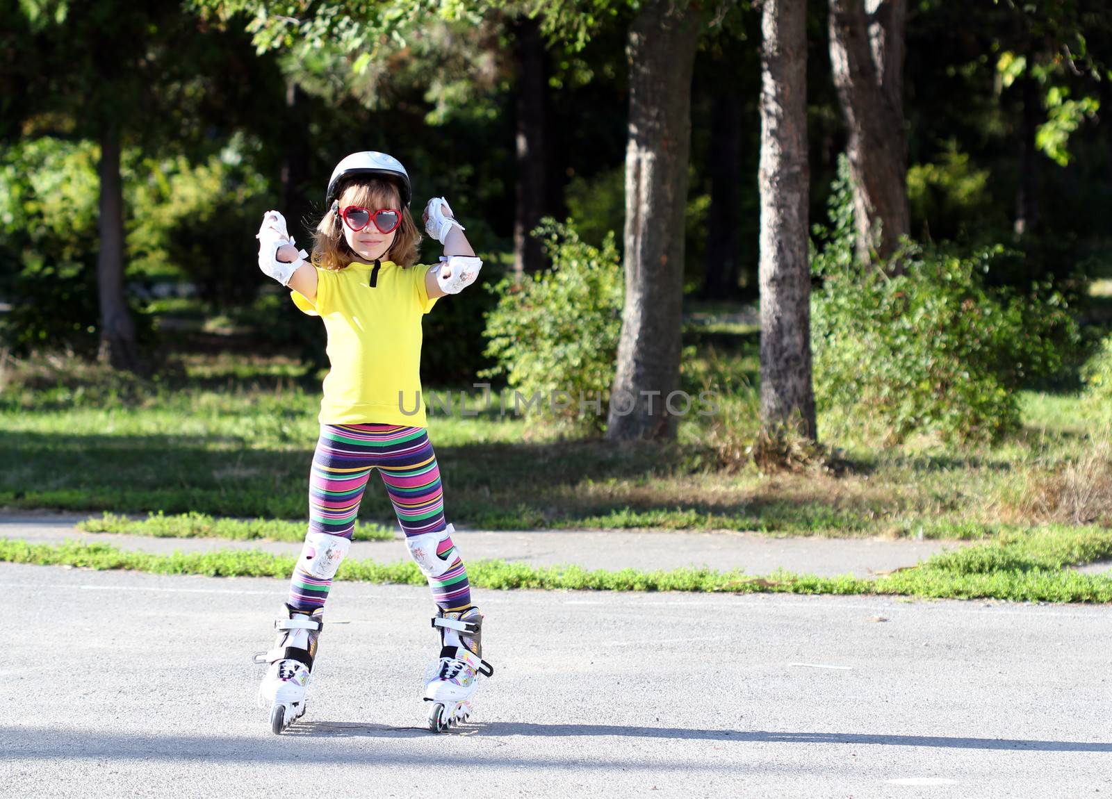 Roller skating happy little girl with protective gear by goce