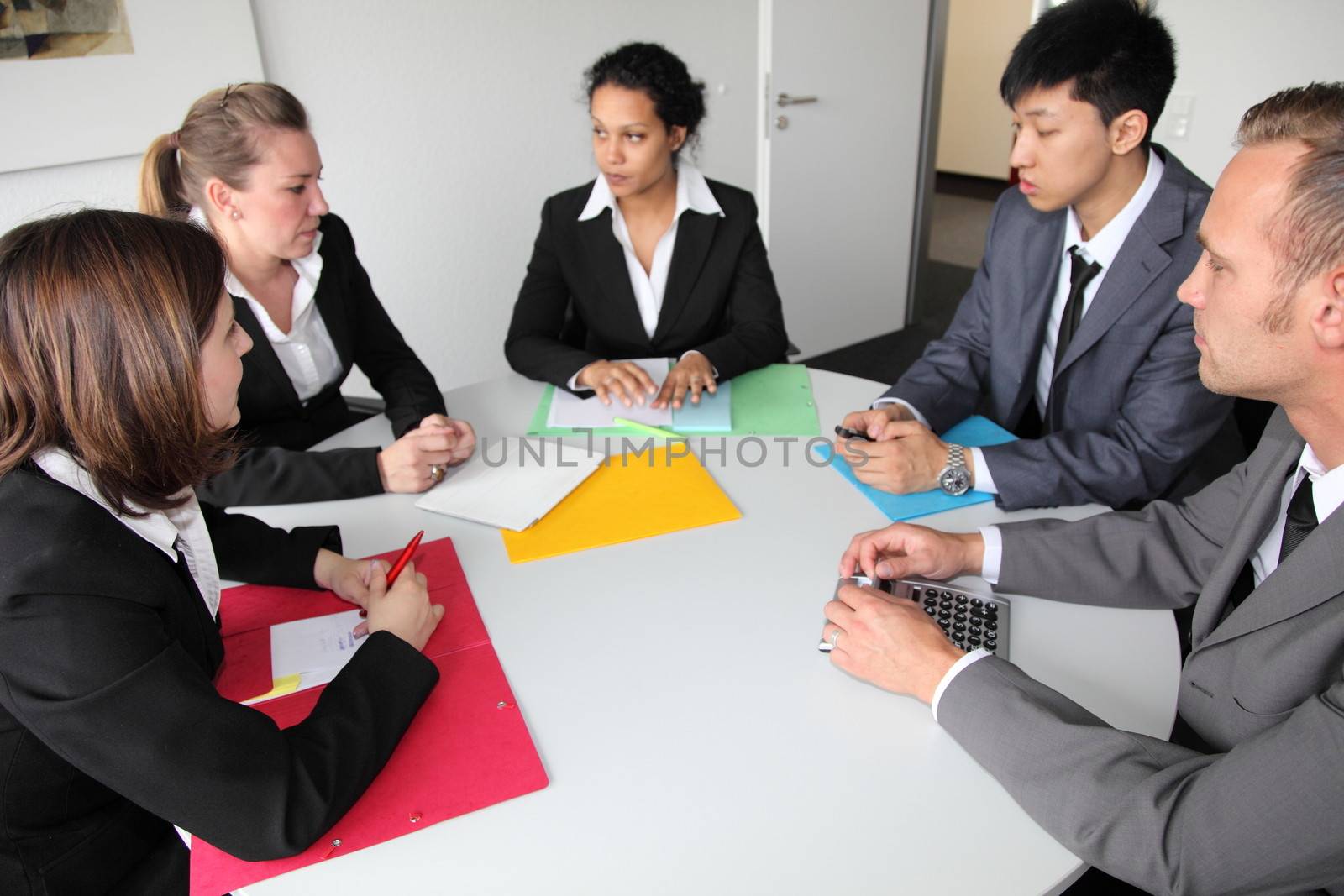 Group of serious young multiethnic business people in a meeting seated around a table discussing a problem