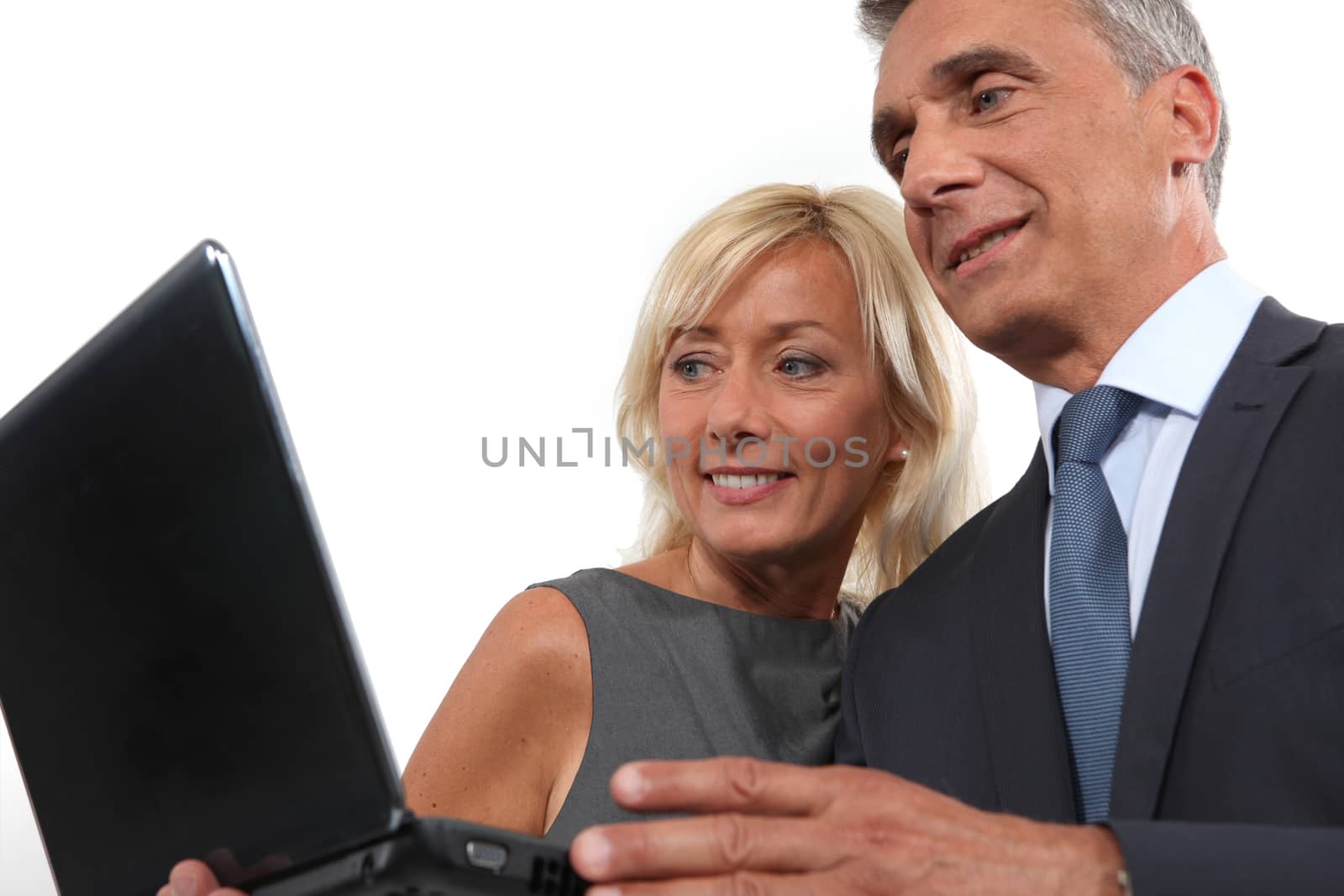 happy businessman and businesswoman looking at a laptop by phovoir