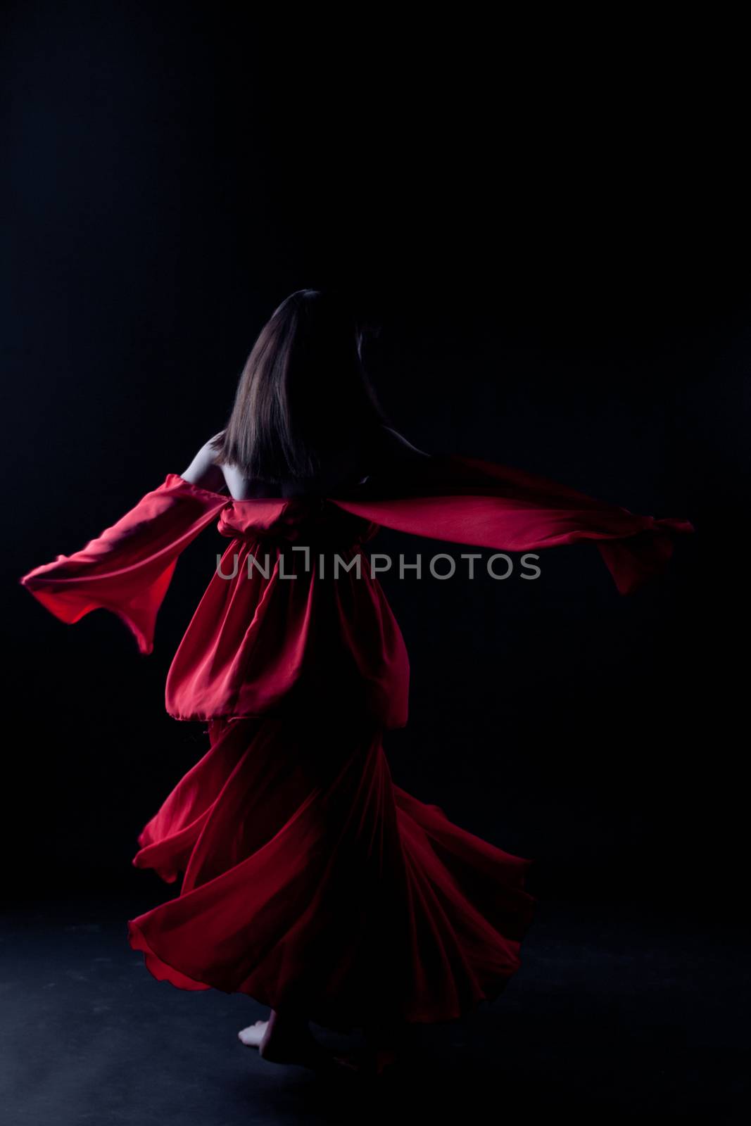 Young girl in red dancer in a darkness
