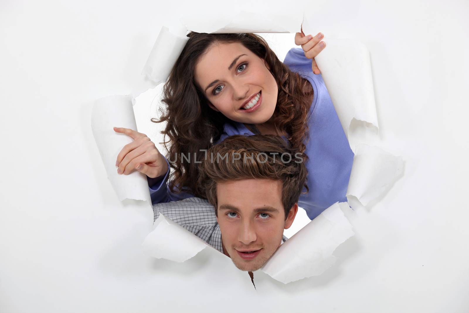 Couple peeking through hole in paper