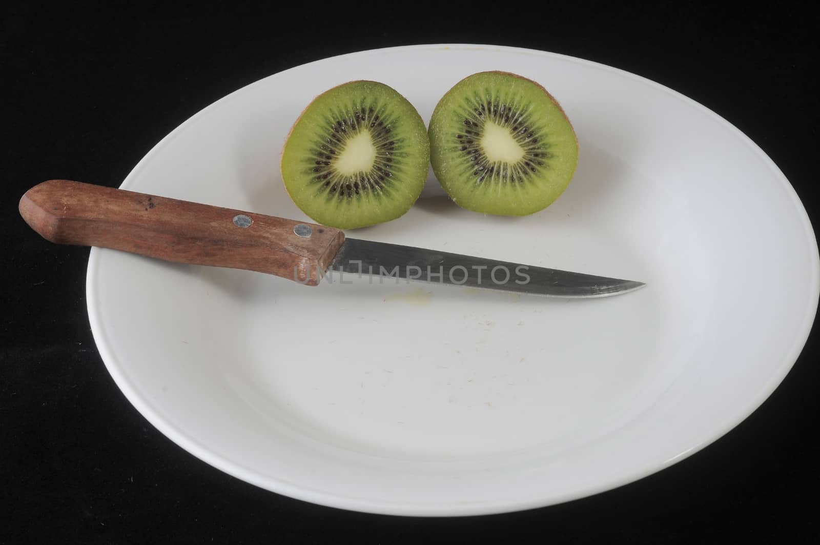 Cutting a Green and Brown Kiwi in Two Parts