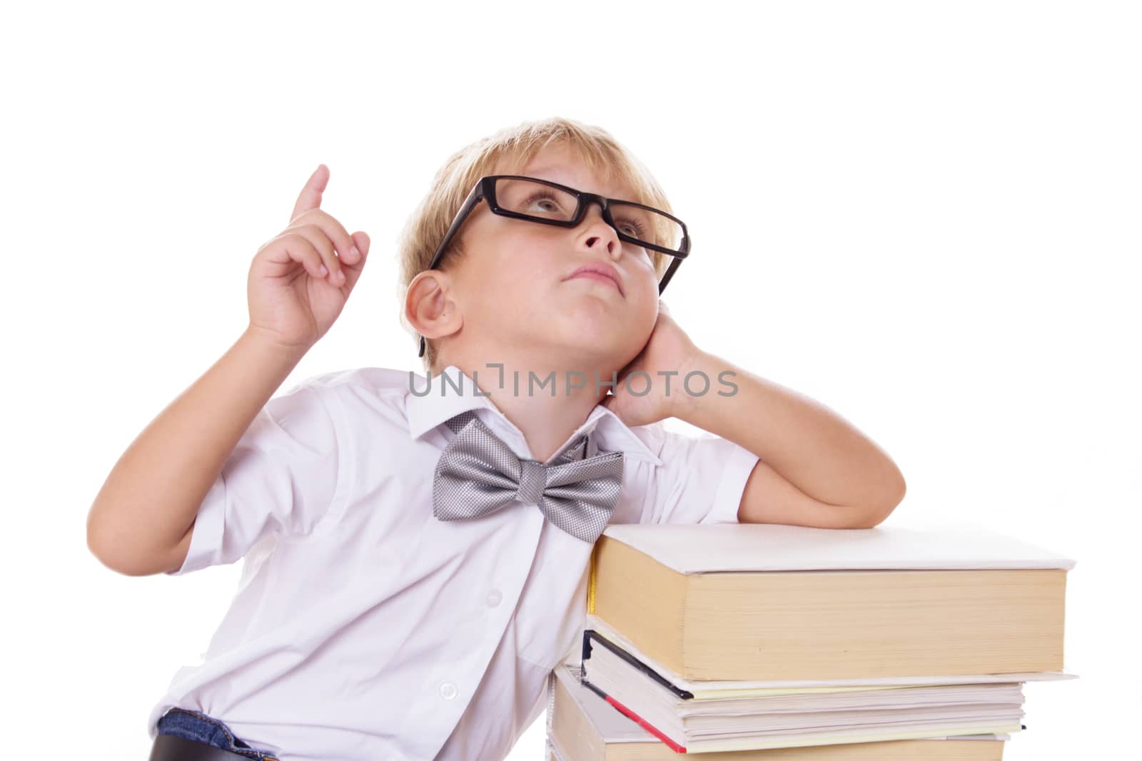 Boy with bow-tie and glasses sitting on books raising finger up over white