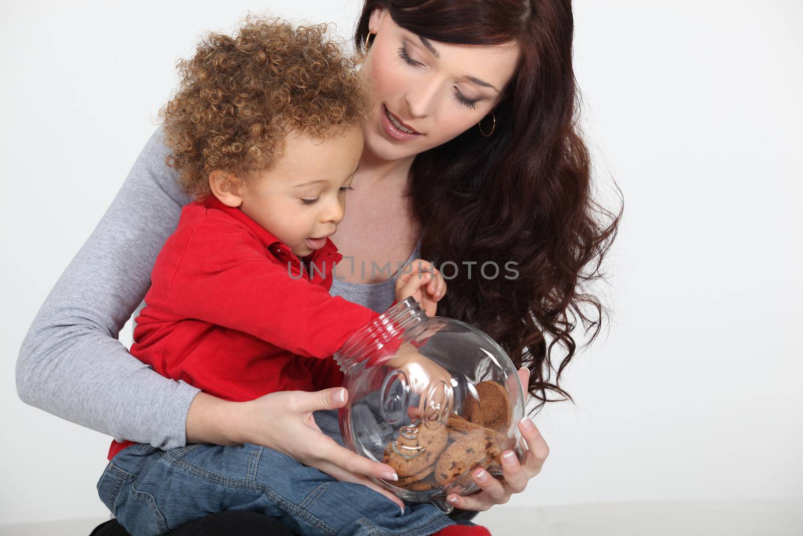 Little boy grabbing biscuit from jar by phovoir