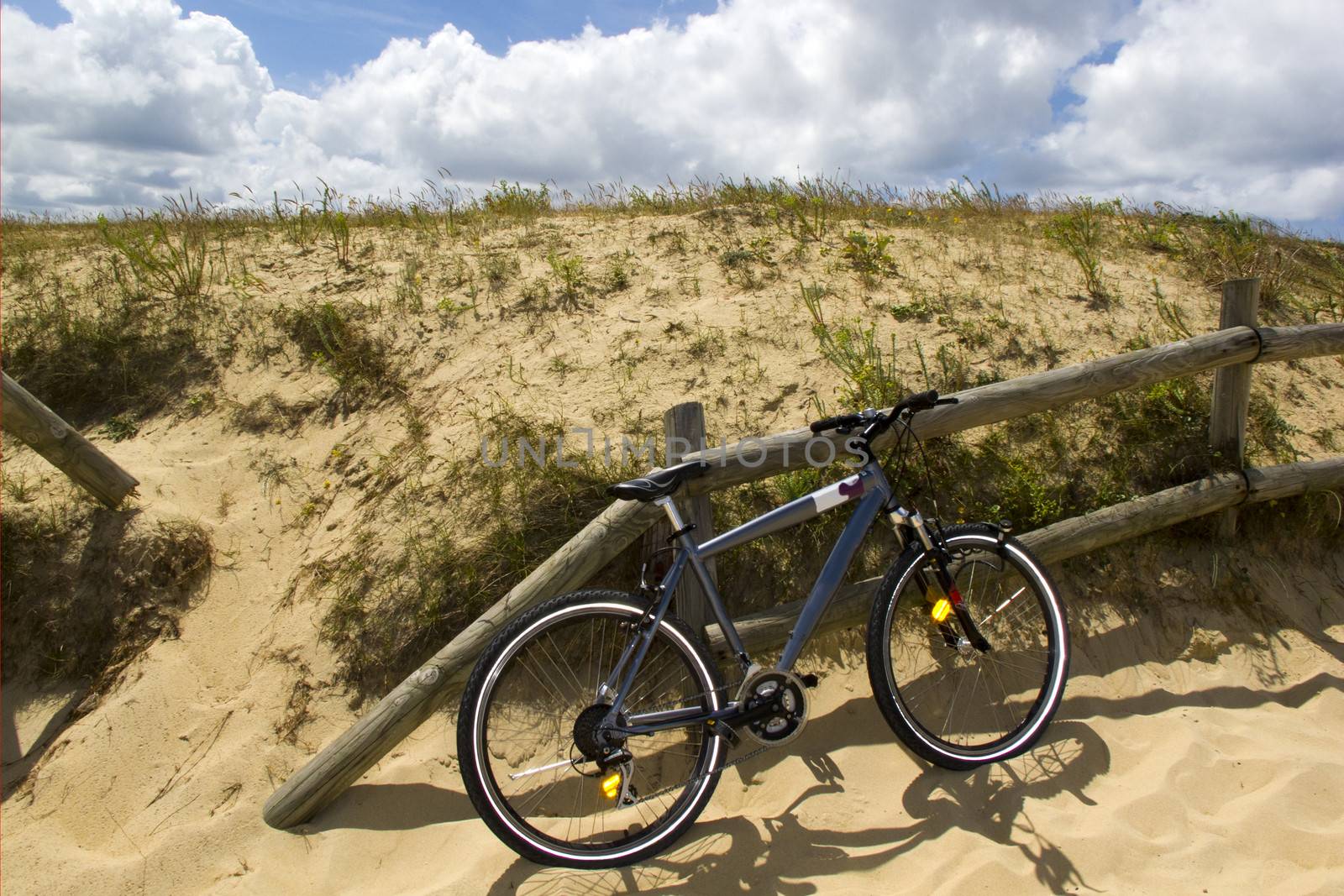 a bike parked at a fence by the dunes